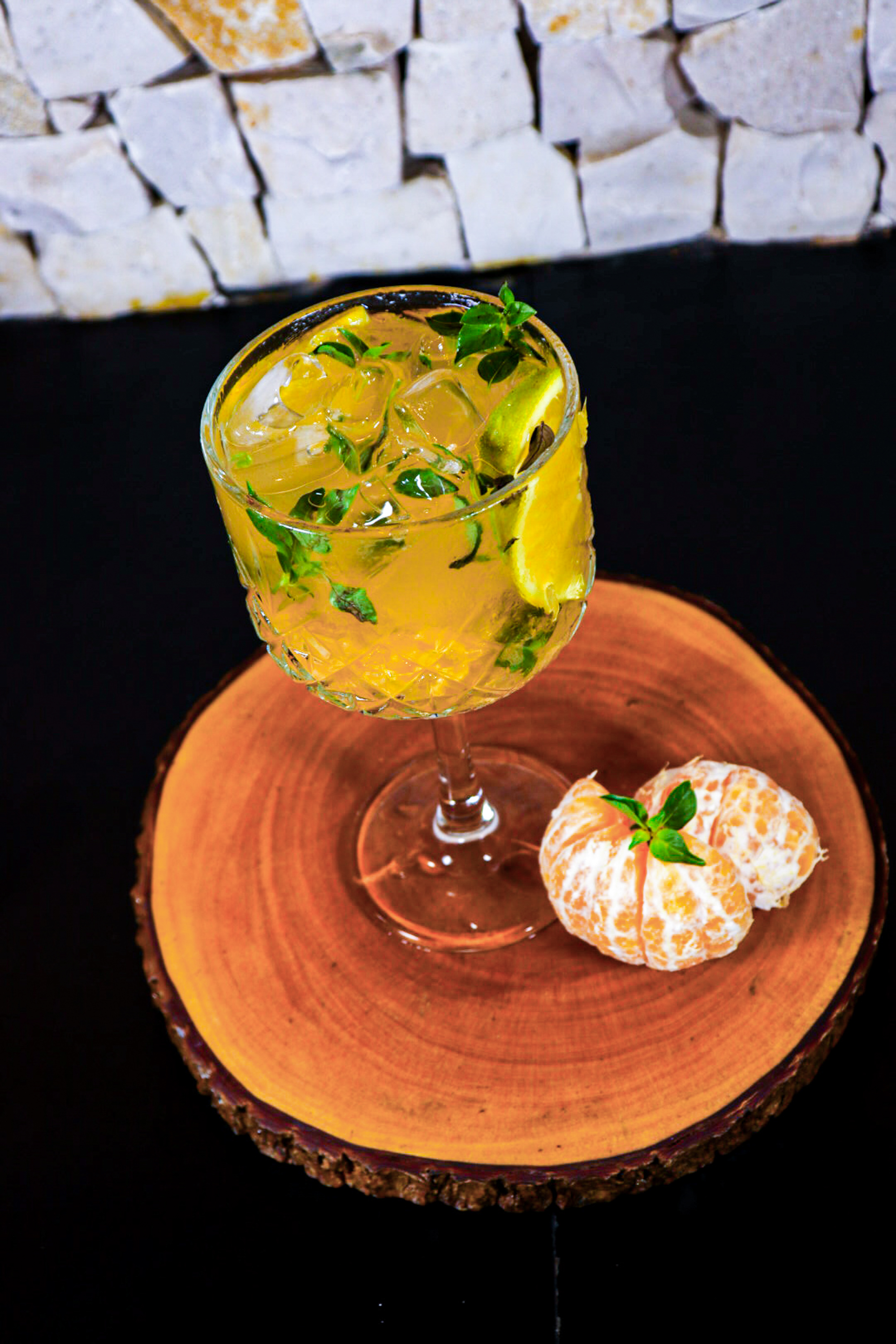 a glass of liquid with ice and mint on a wood surface