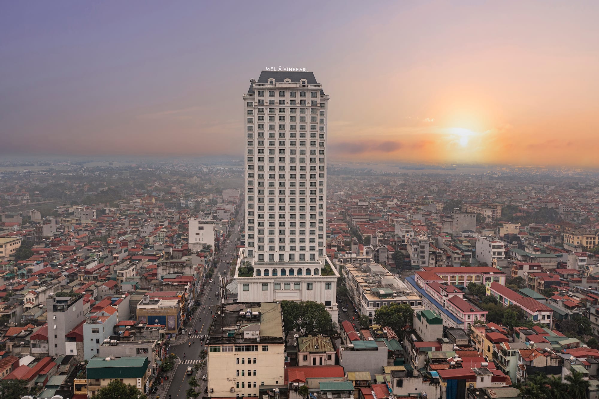 Melia Vinpearl hotel high-rise in urban cityscape at sunset.