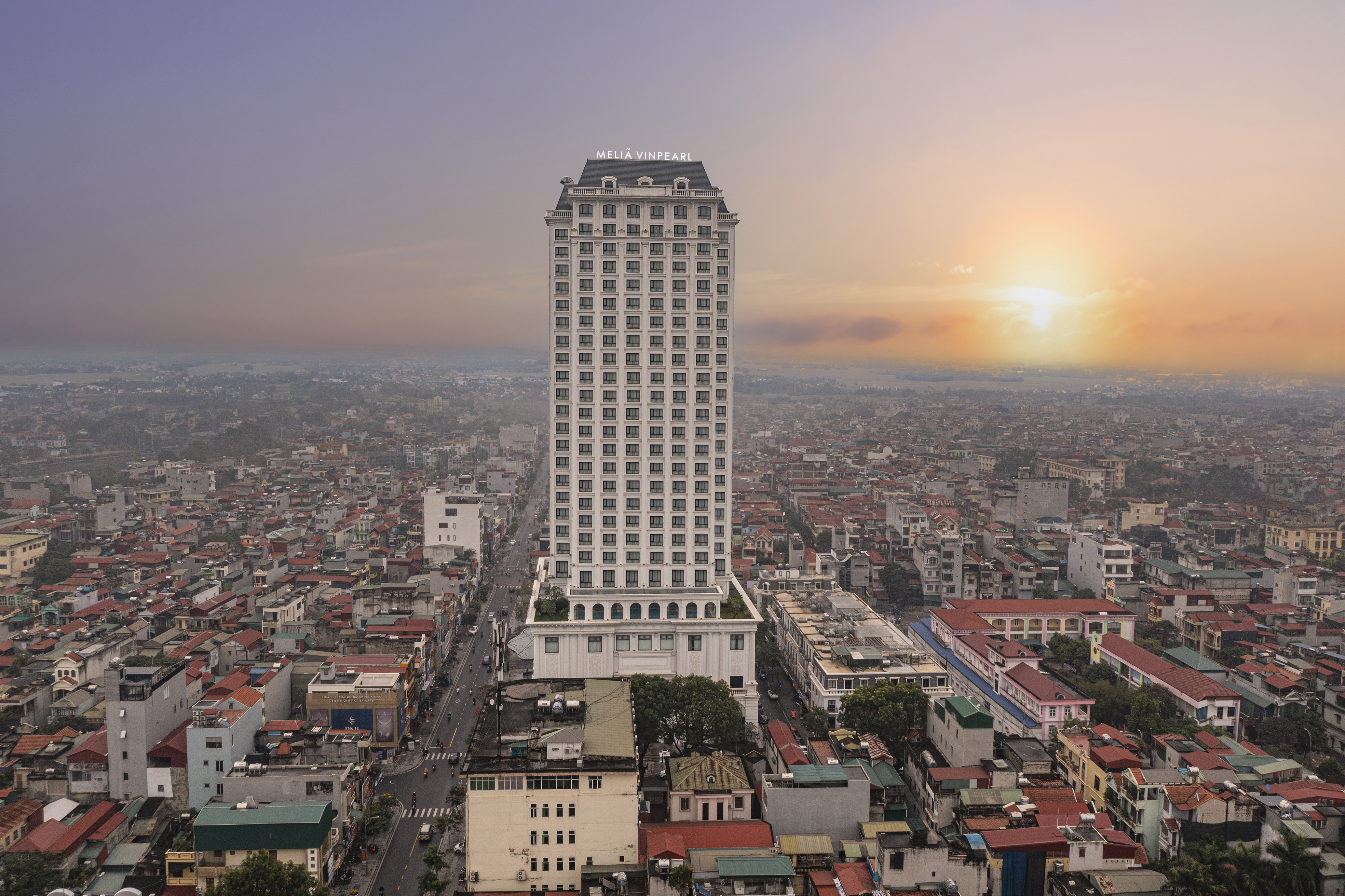 Melia Vinpearl hotel high-rise in urban cityscape at sunset.