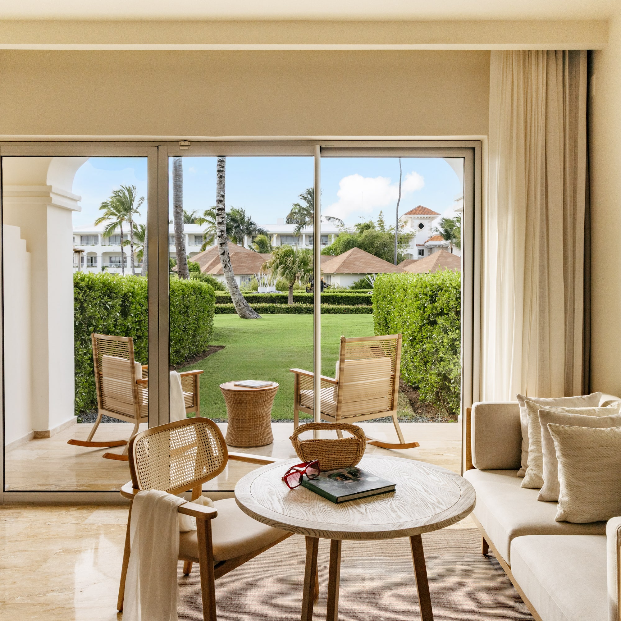 Luxury hotel suite living room with patio garden view and tropical trees.