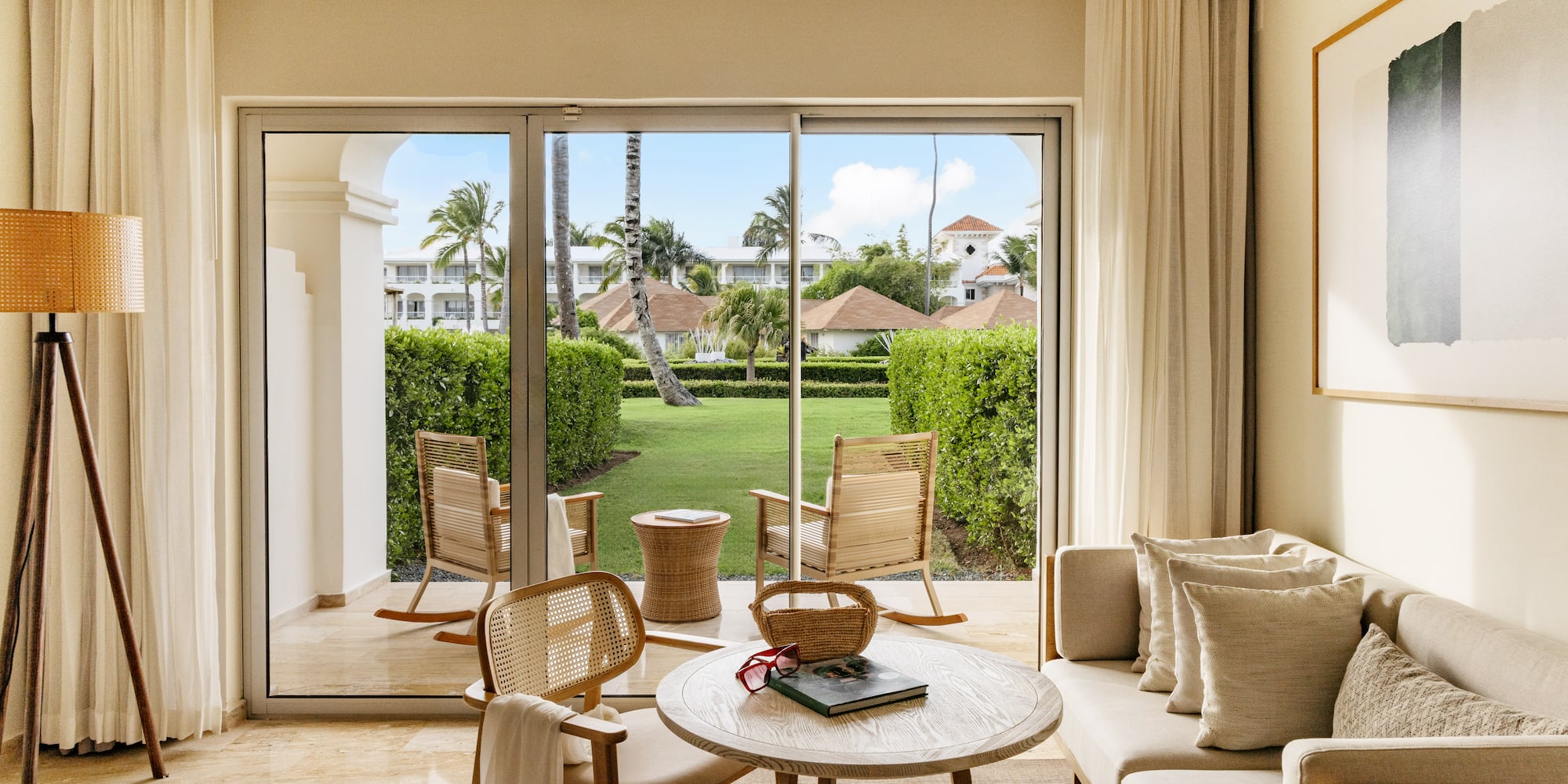 Luxury hotel suite living room with patio garden view and tropical trees.