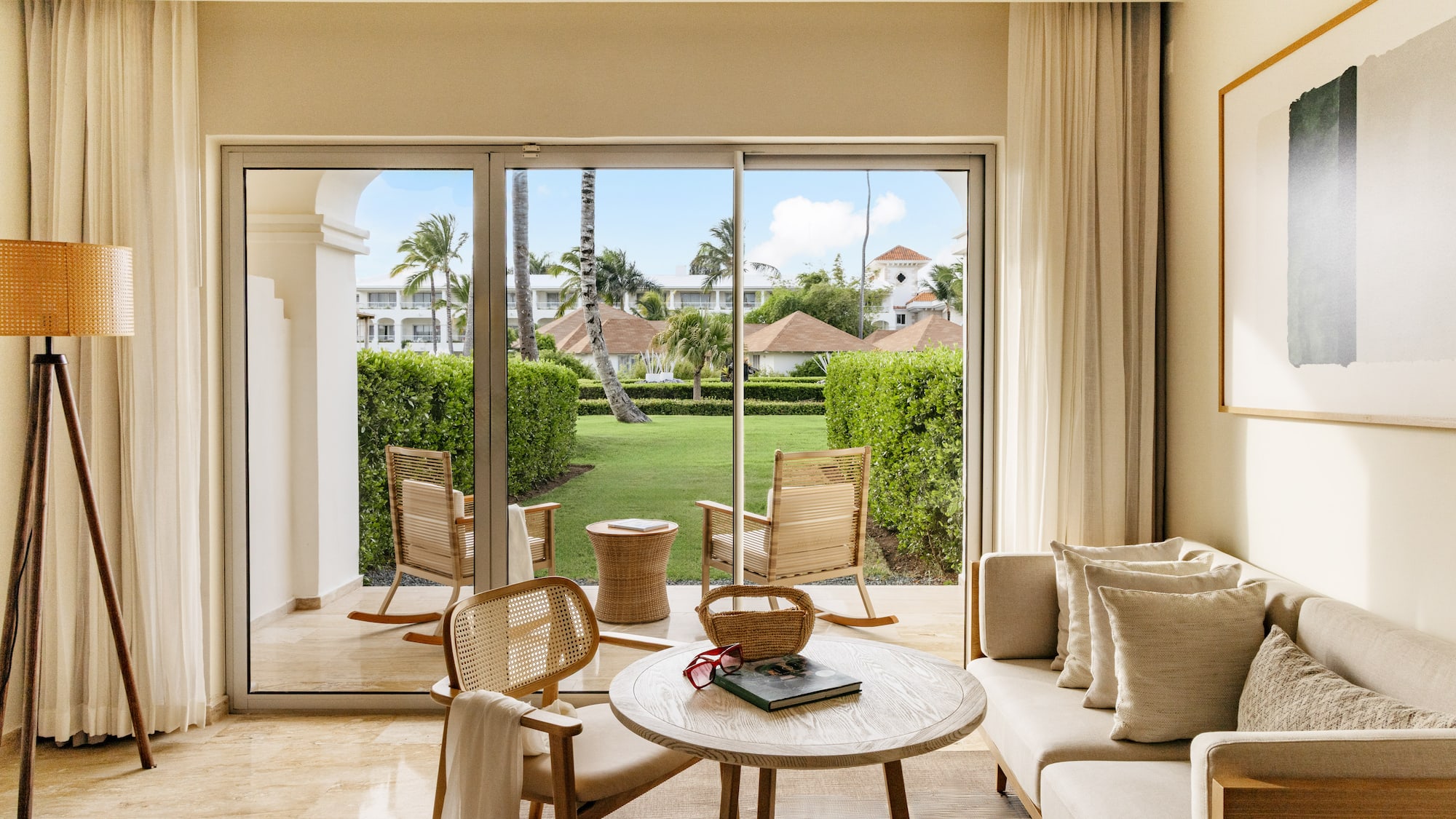 Luxury hotel suite living room with patio garden view and tropical trees.