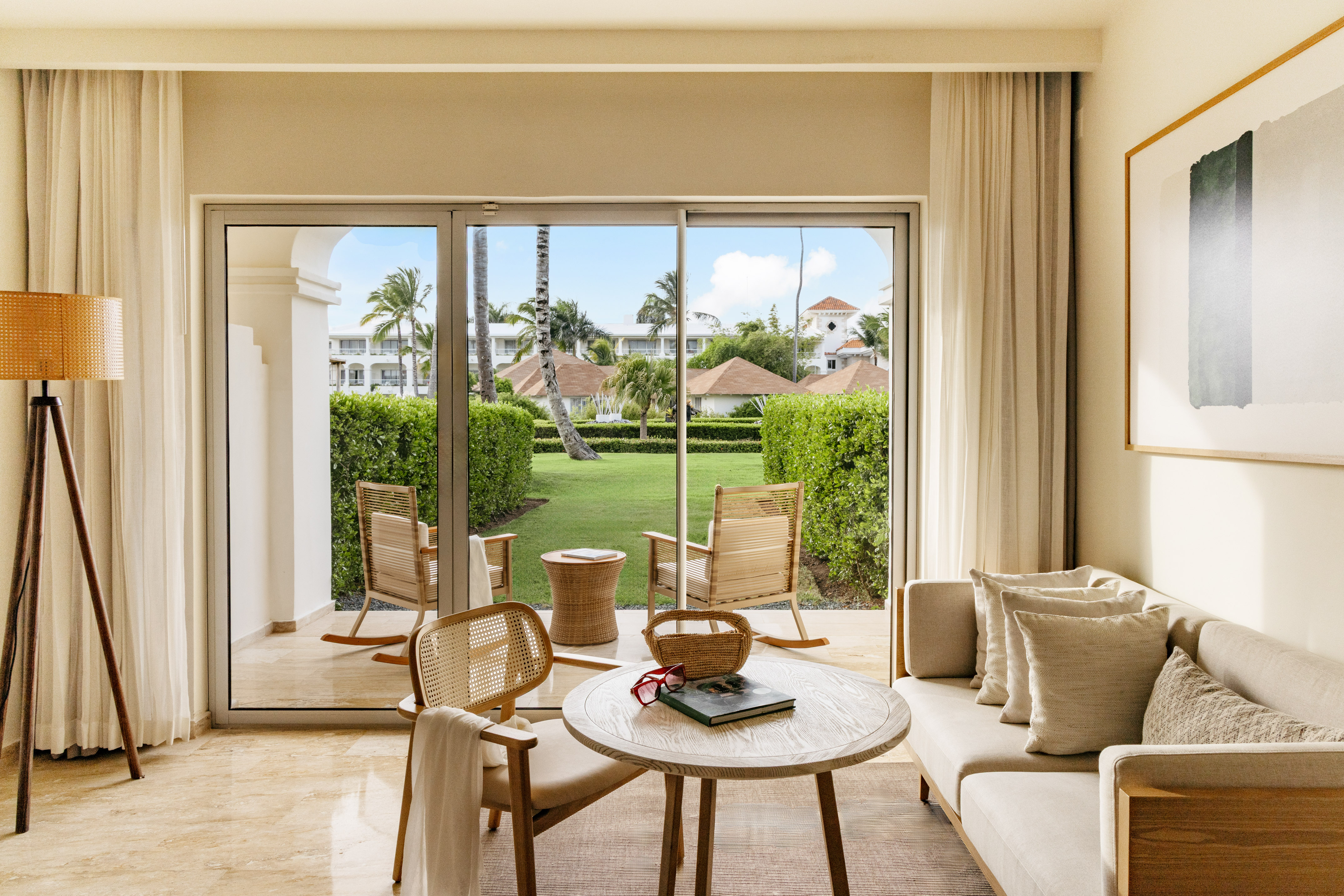 Luxury hotel suite living room with patio garden view and tropical trees.