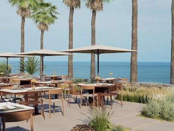 a tables and chairs outside with a beach and palm trees