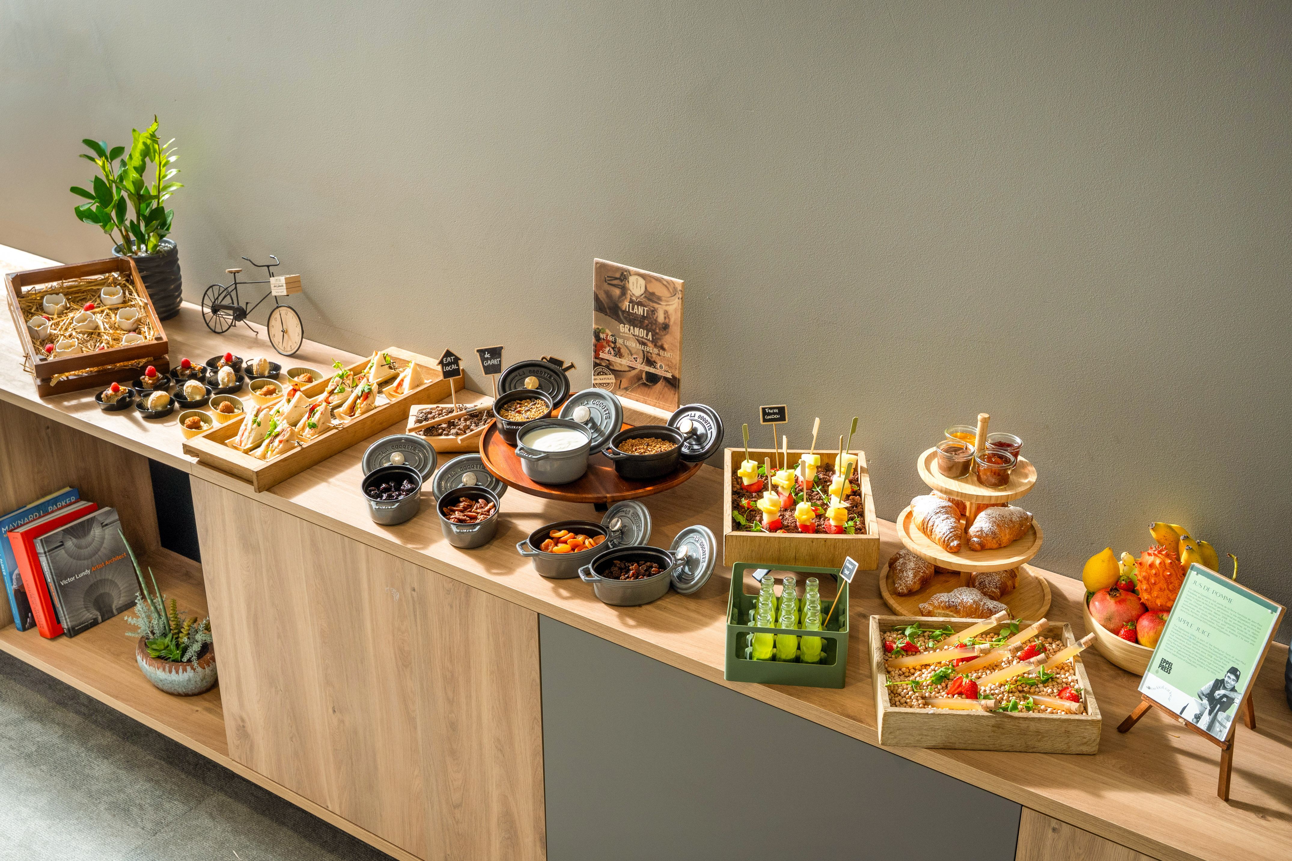 Breakfast buffet with granola, yogurt, fruit, pastries, and sandwiches.
