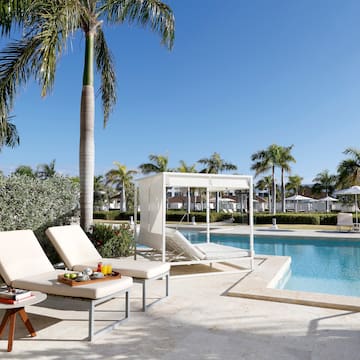 een zwembad met ligstoelen en palmbomen