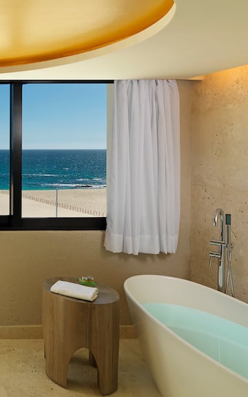 a bathroom with a bathtub and a window overlooking the ocean