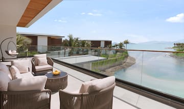 a patio with chairs and a table overlooking a body of water