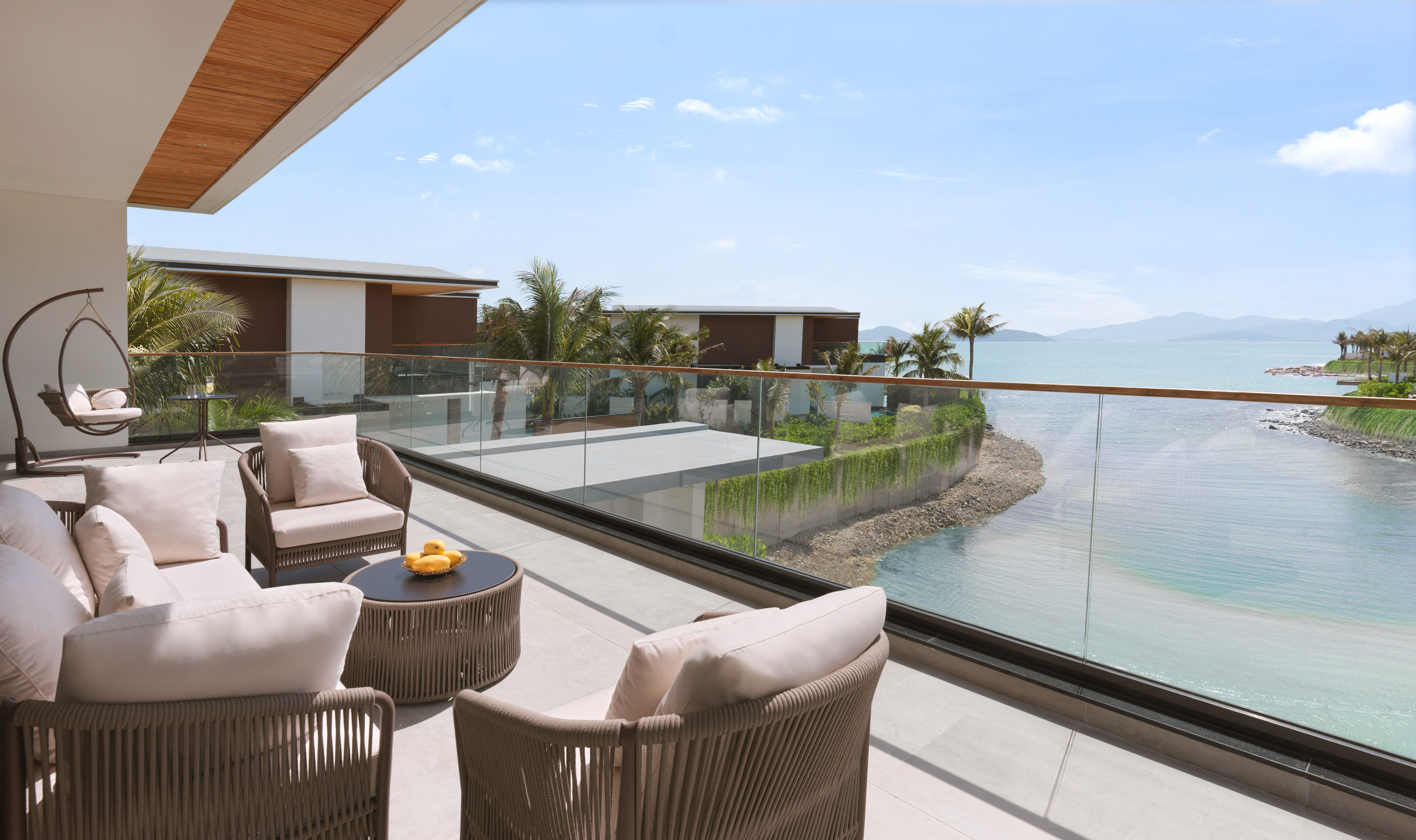 Luxury resort balcony with ocean view, modern outdoor furniture, and palm trees.
