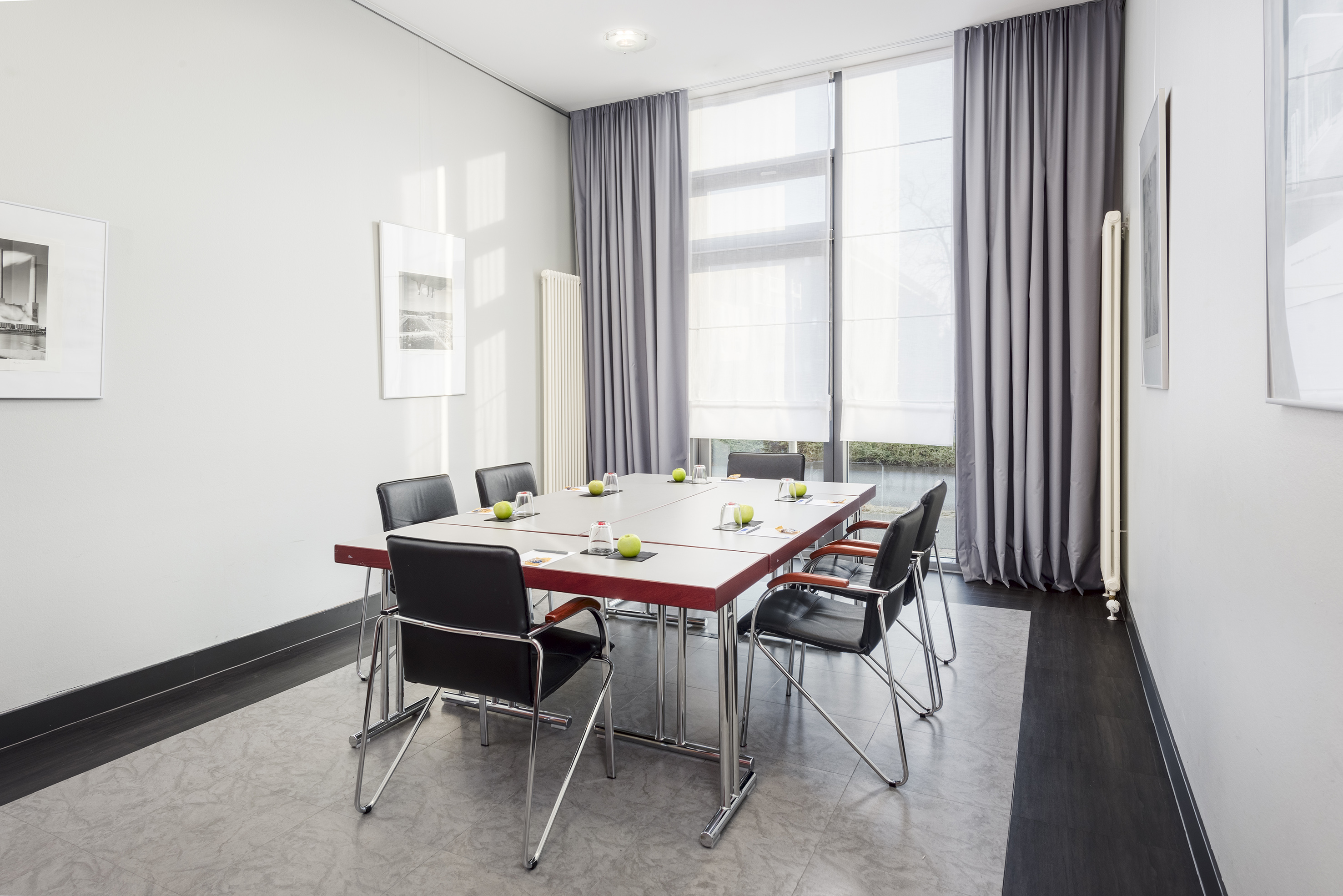 Professional meeting room with modern table, black chairs, and natural light.