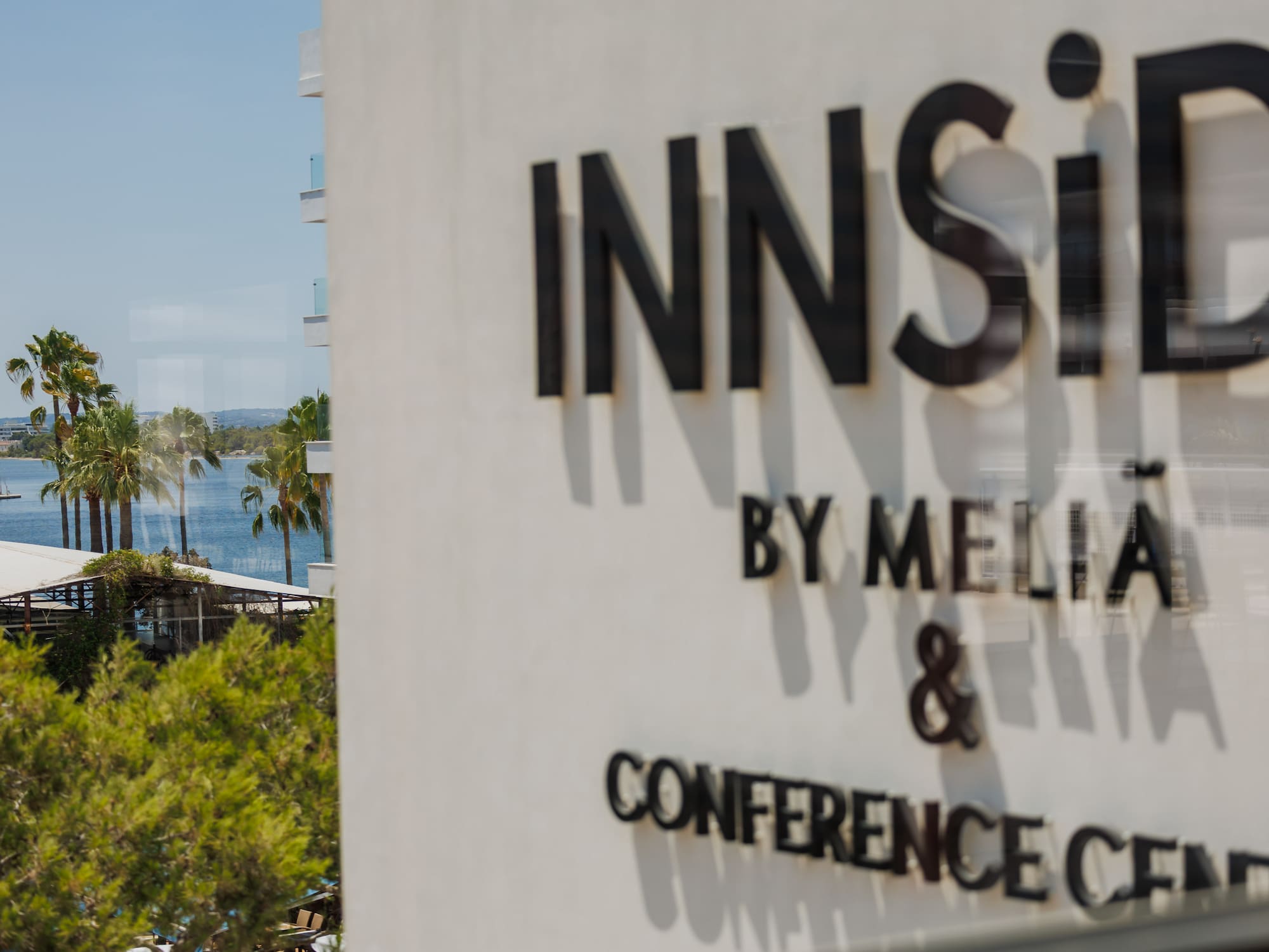 INNSiDE by Meliã Conference Center sign with sunny coastal view and palm trees.
