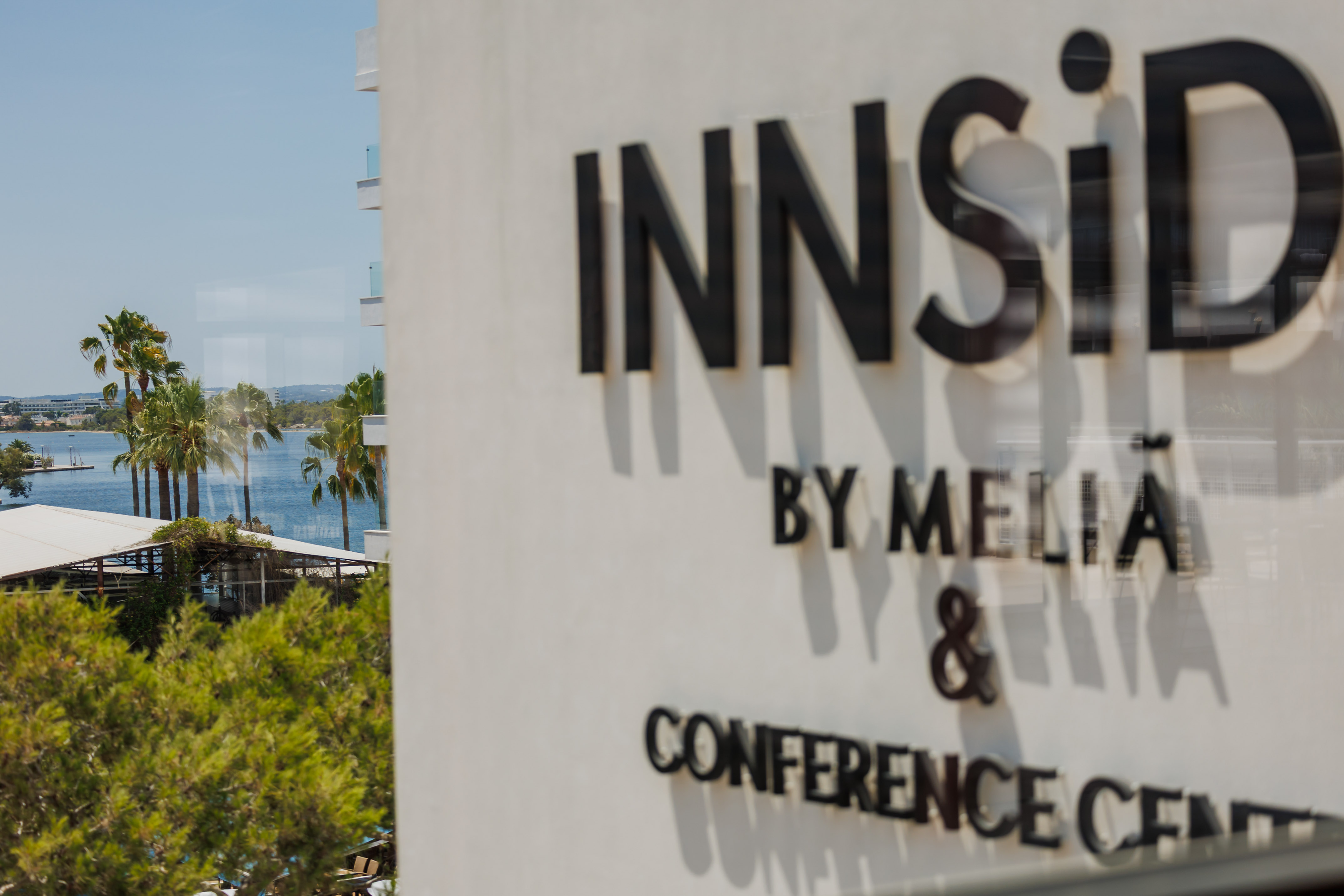 INNSiDE by Meliã Conference Center sign with sunny coastal view and palm trees.
