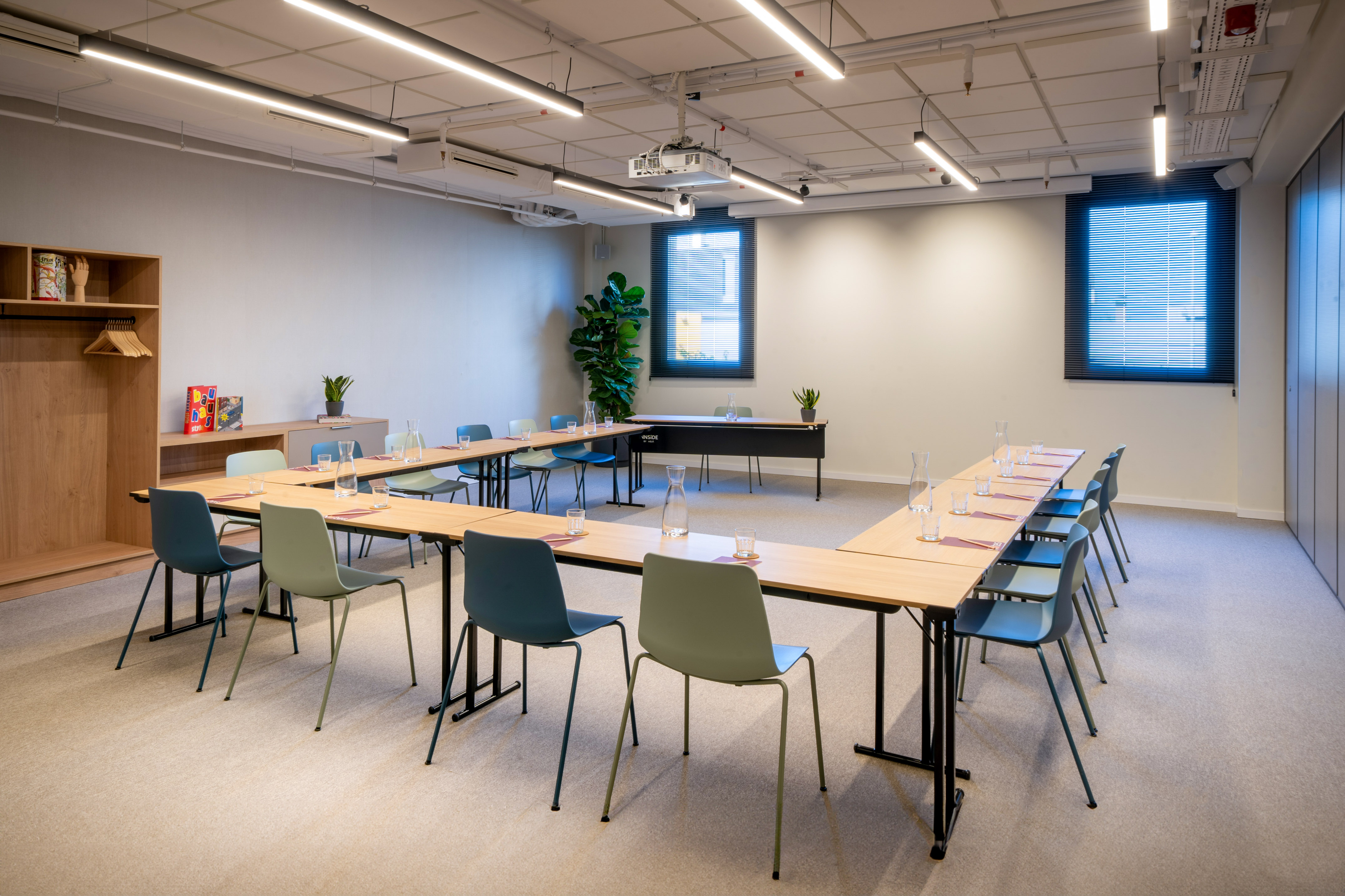 Modern U-shaped meeting room with colorful chairs and ceiling projector.