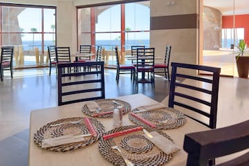 a table with place settings and chairs in a room with a view of the ocean