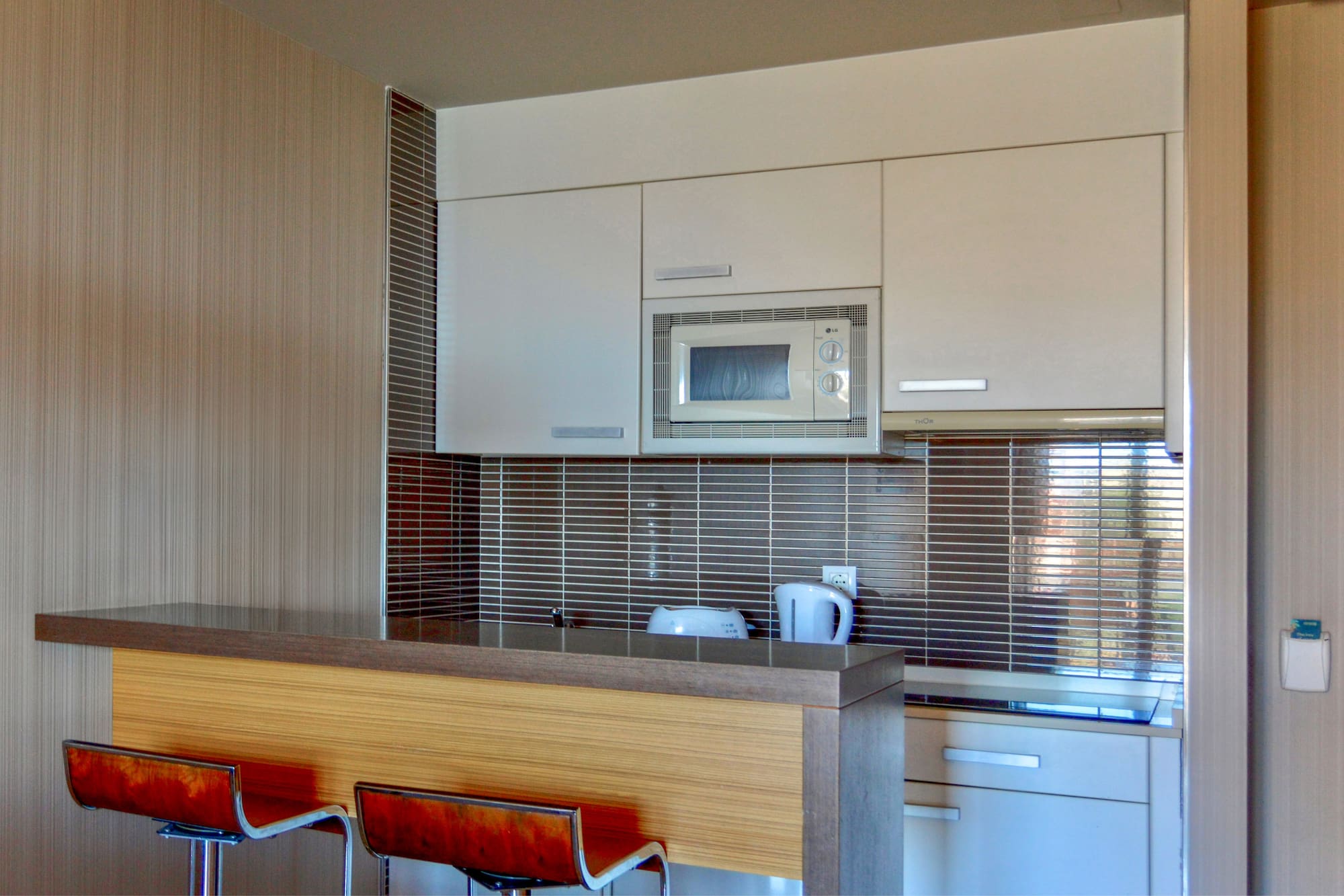 a kitchen with a microwave oven and bar stools