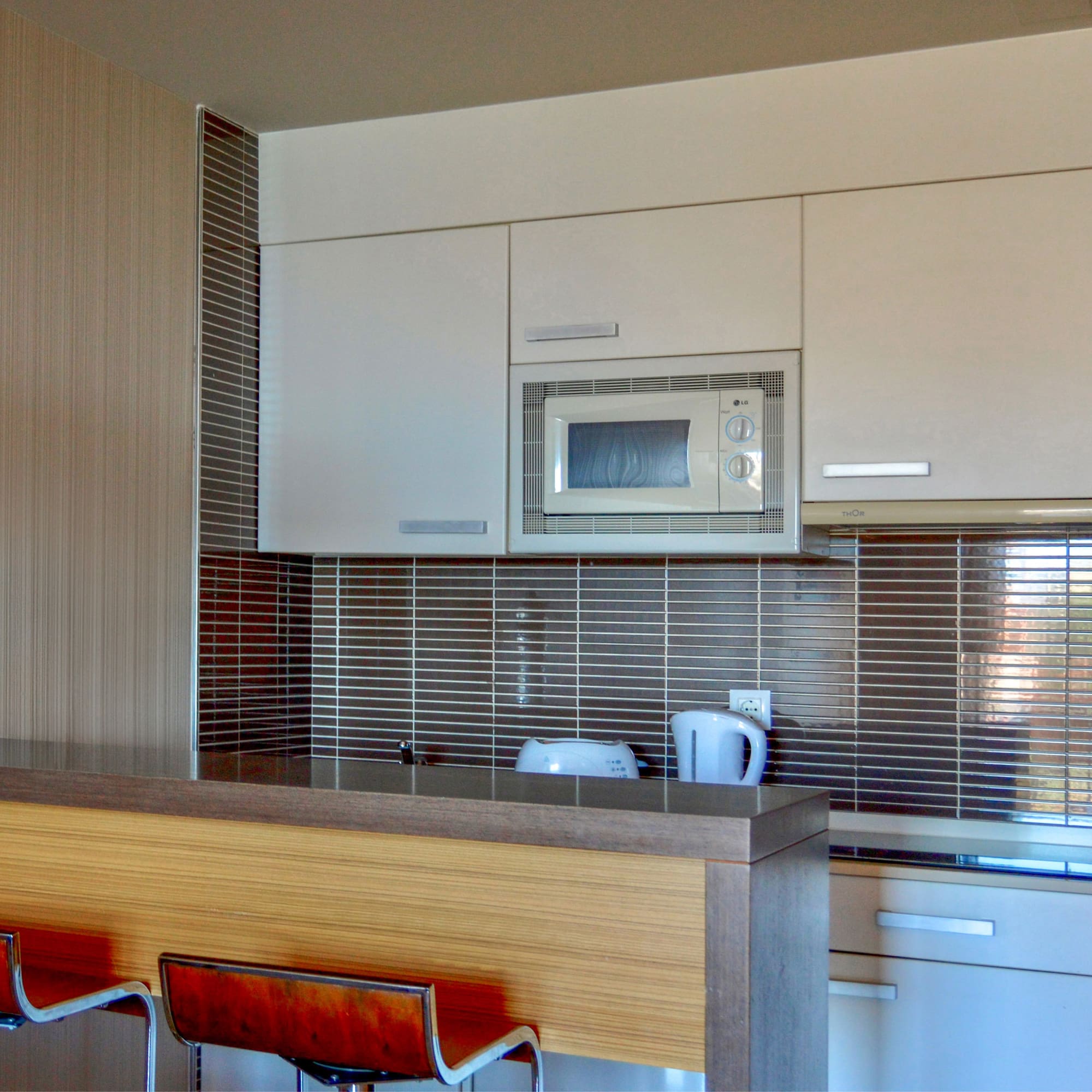 a kitchen with a microwave oven and bar stools