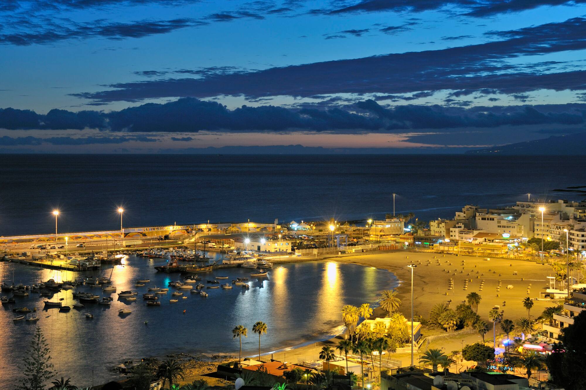 a beach with boats and buildings at night