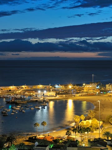 a beach with boats and buildings at night