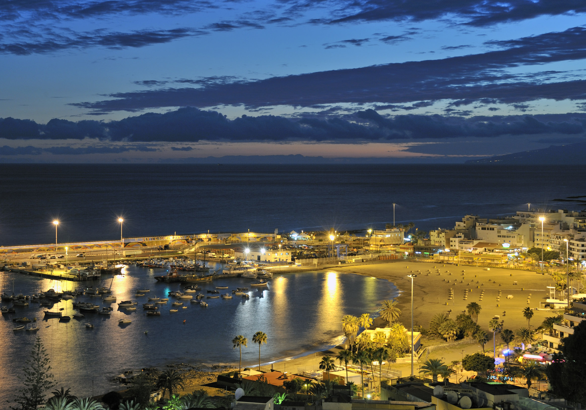 a beach with boats and buildings at night