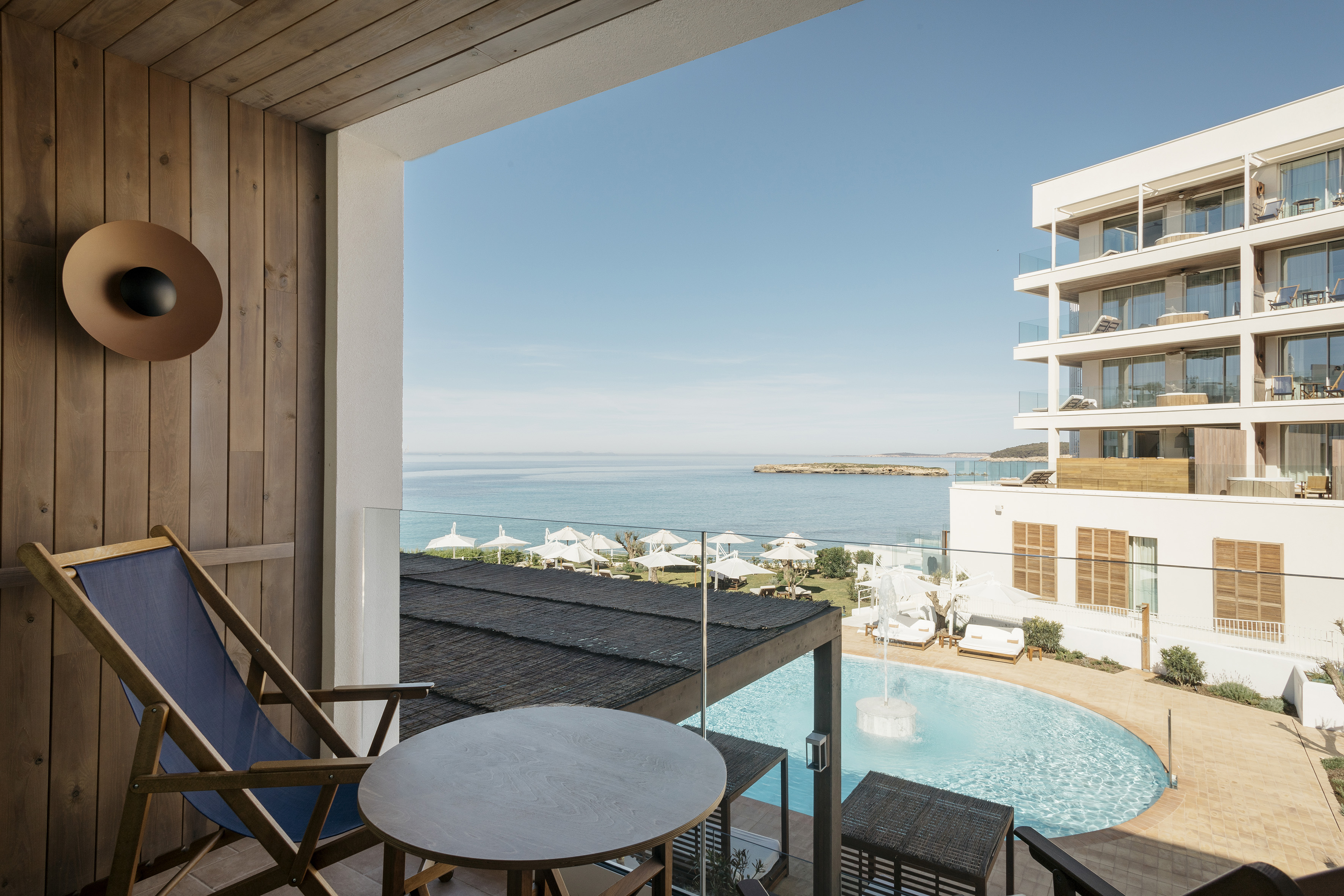 Resort balcony with ocean view, swimming pool, and hotel buildings.