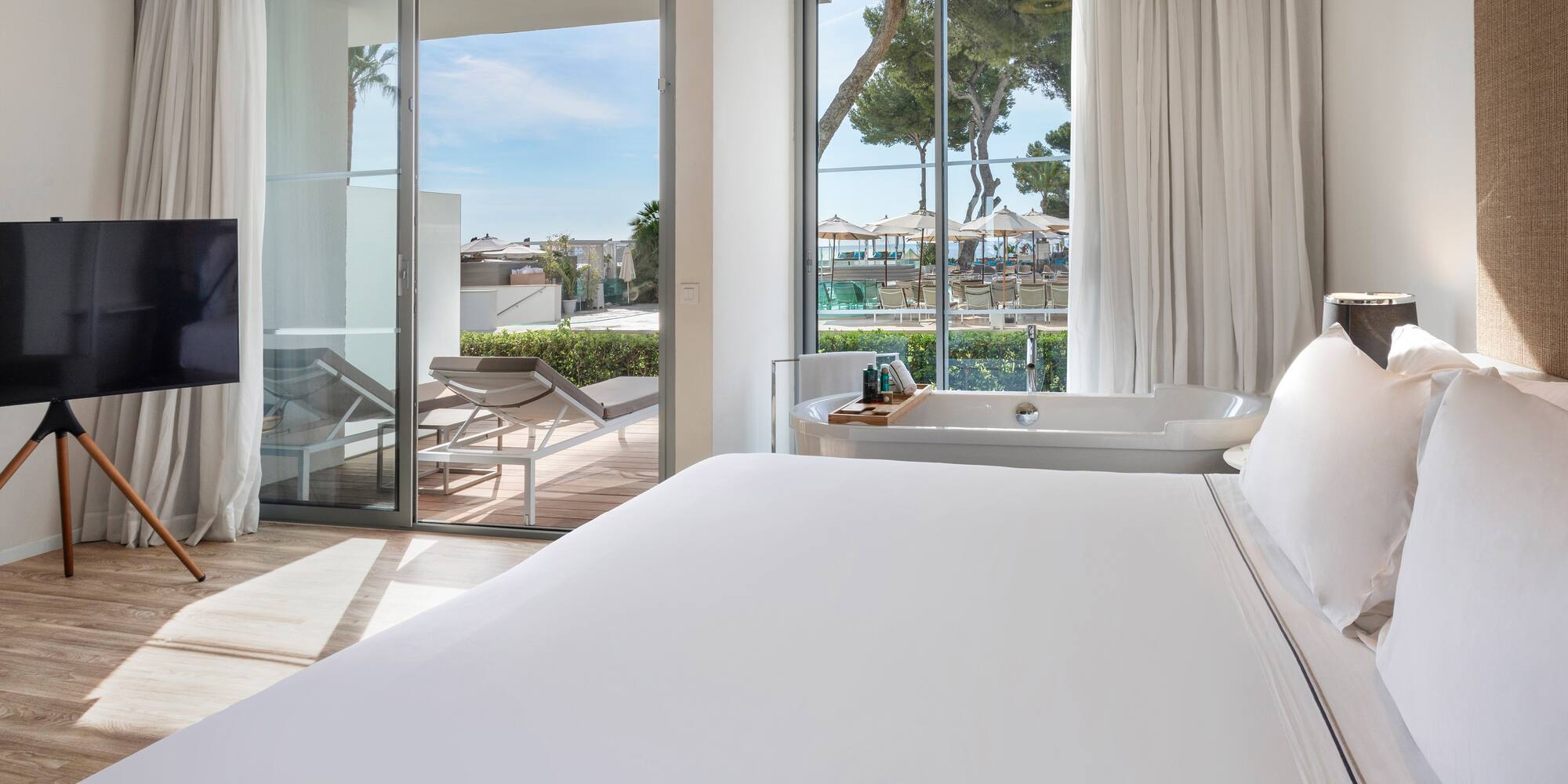 a bed with a bathtub and a tub in a room with glass doors