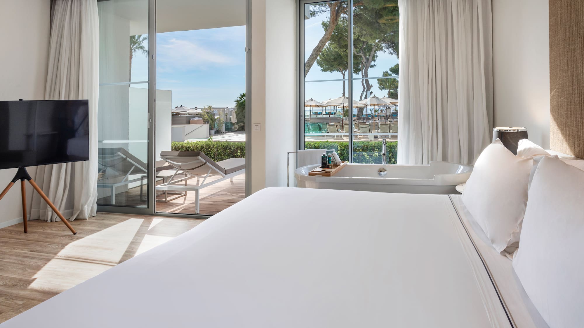 a bed with a bathtub and a tub in a room with glass doors