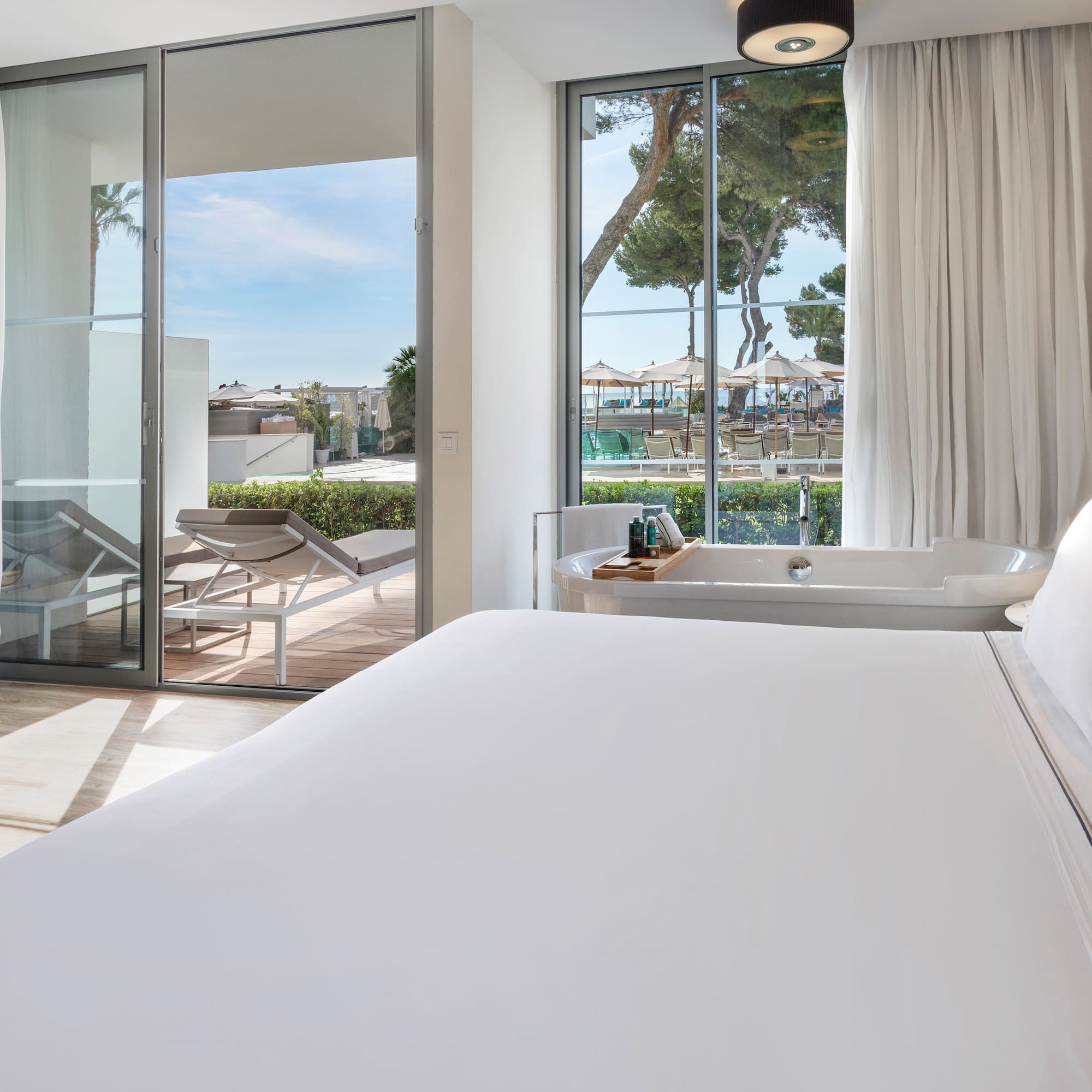 a bed with a bathtub and a tub in a room with glass doors