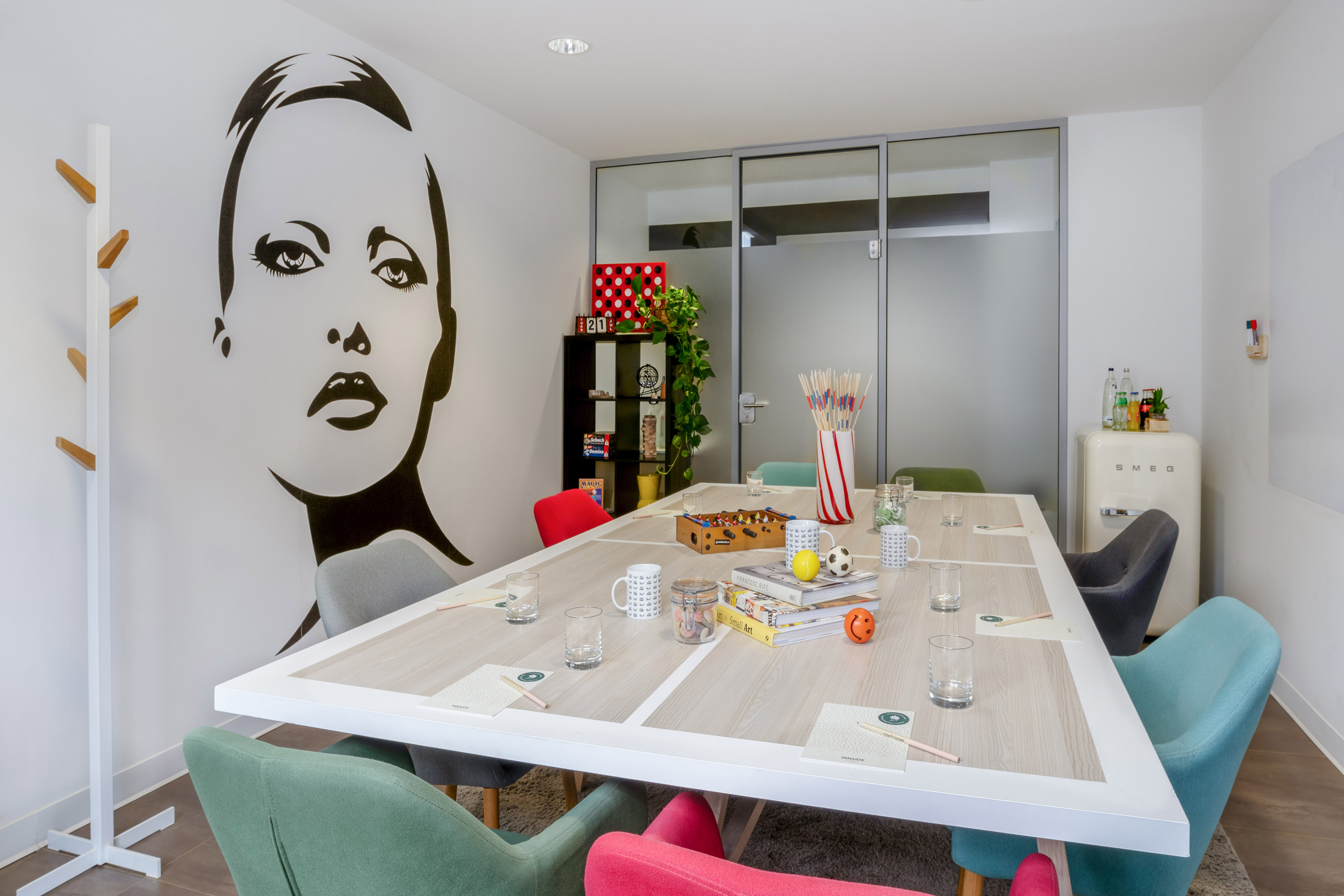 Creative meeting room with pop art mural, colorful chairs, and games table.