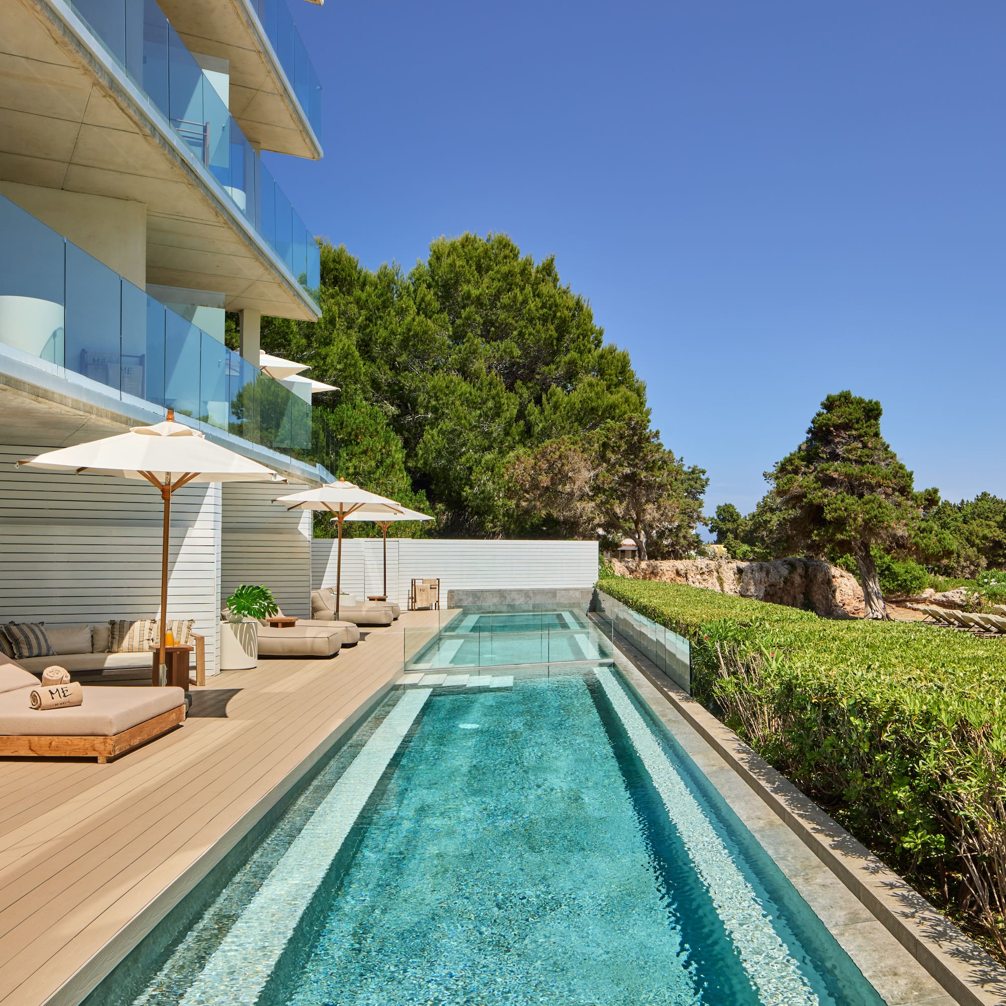 Modern luxury hotel with pool, sun loungers, and sea view terrace.