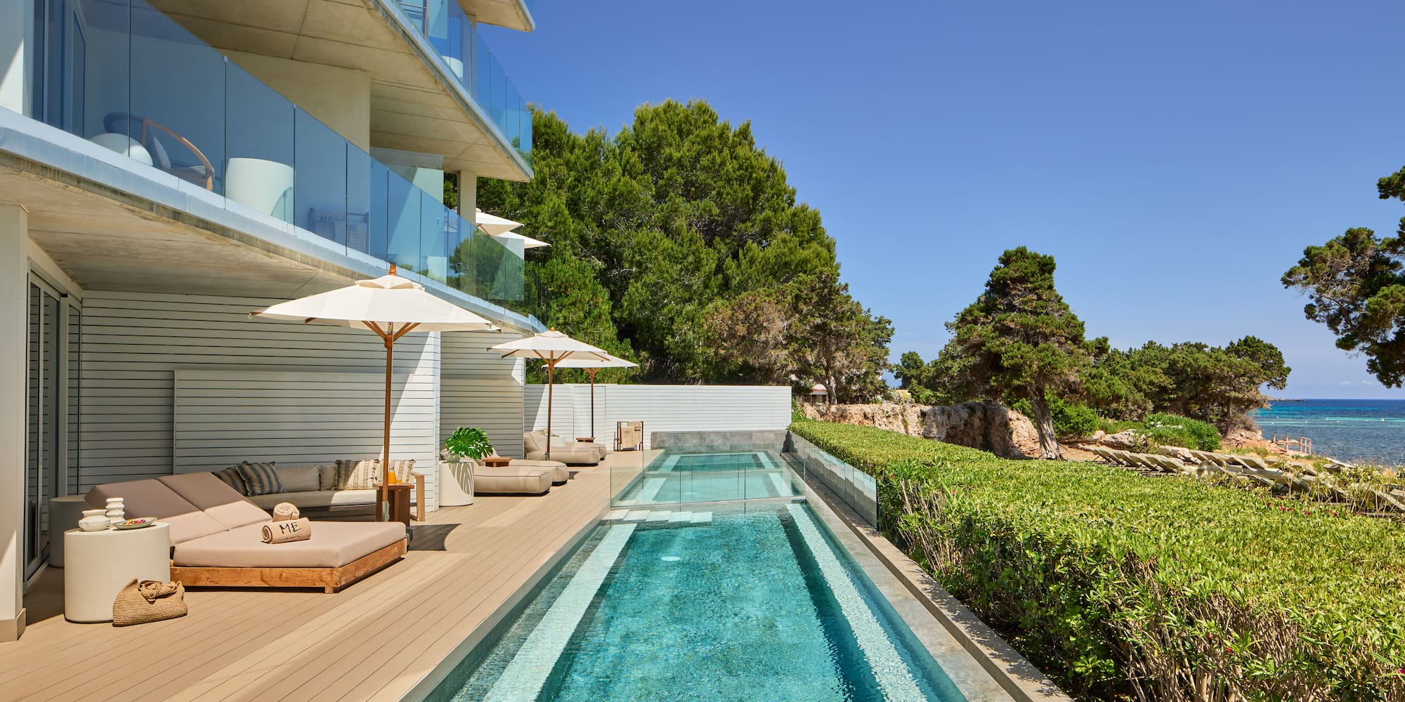 Modern luxury hotel with pool, sun loungers, and sea view terrace.