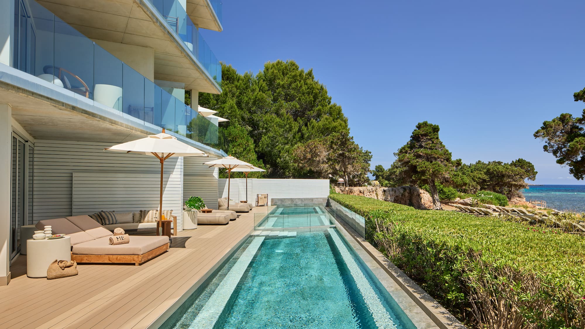 Modern luxury hotel with pool, sun loungers, and sea view terrace.
