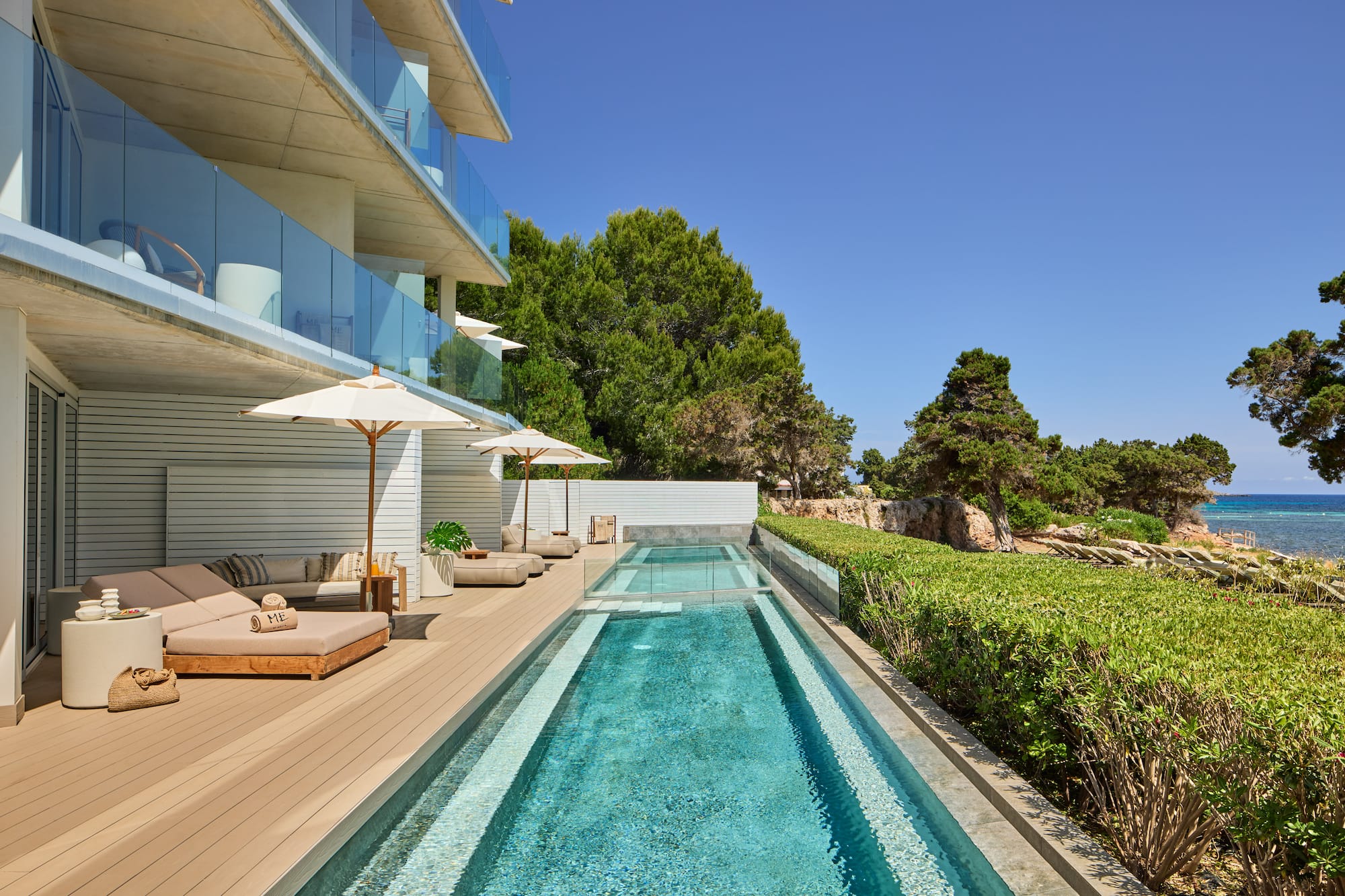 Modern luxury hotel with pool, sun loungers, and sea view terrace.
