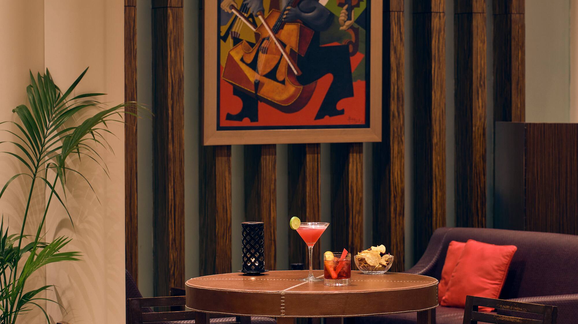a table with a drink and chairs in a room with a painting on the wall