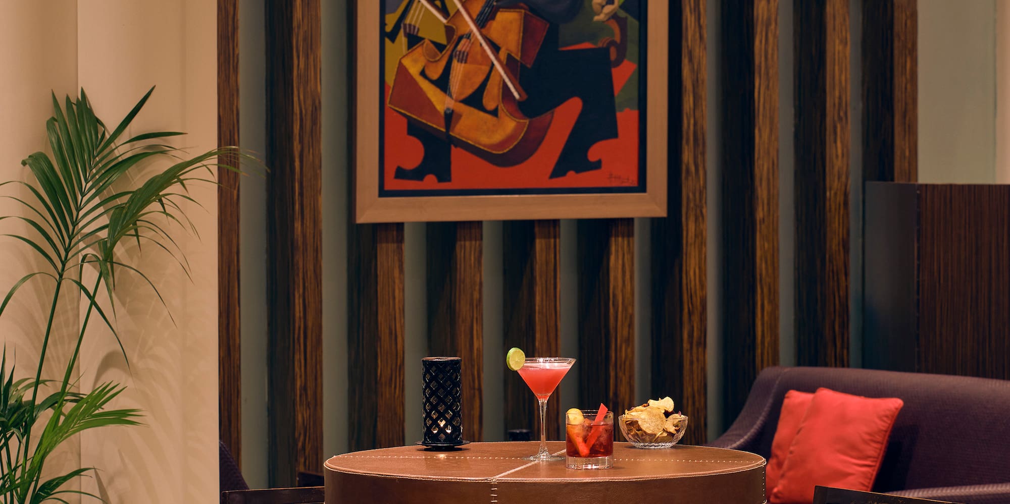 a table with a drink and chairs in a room with a painting on the wall