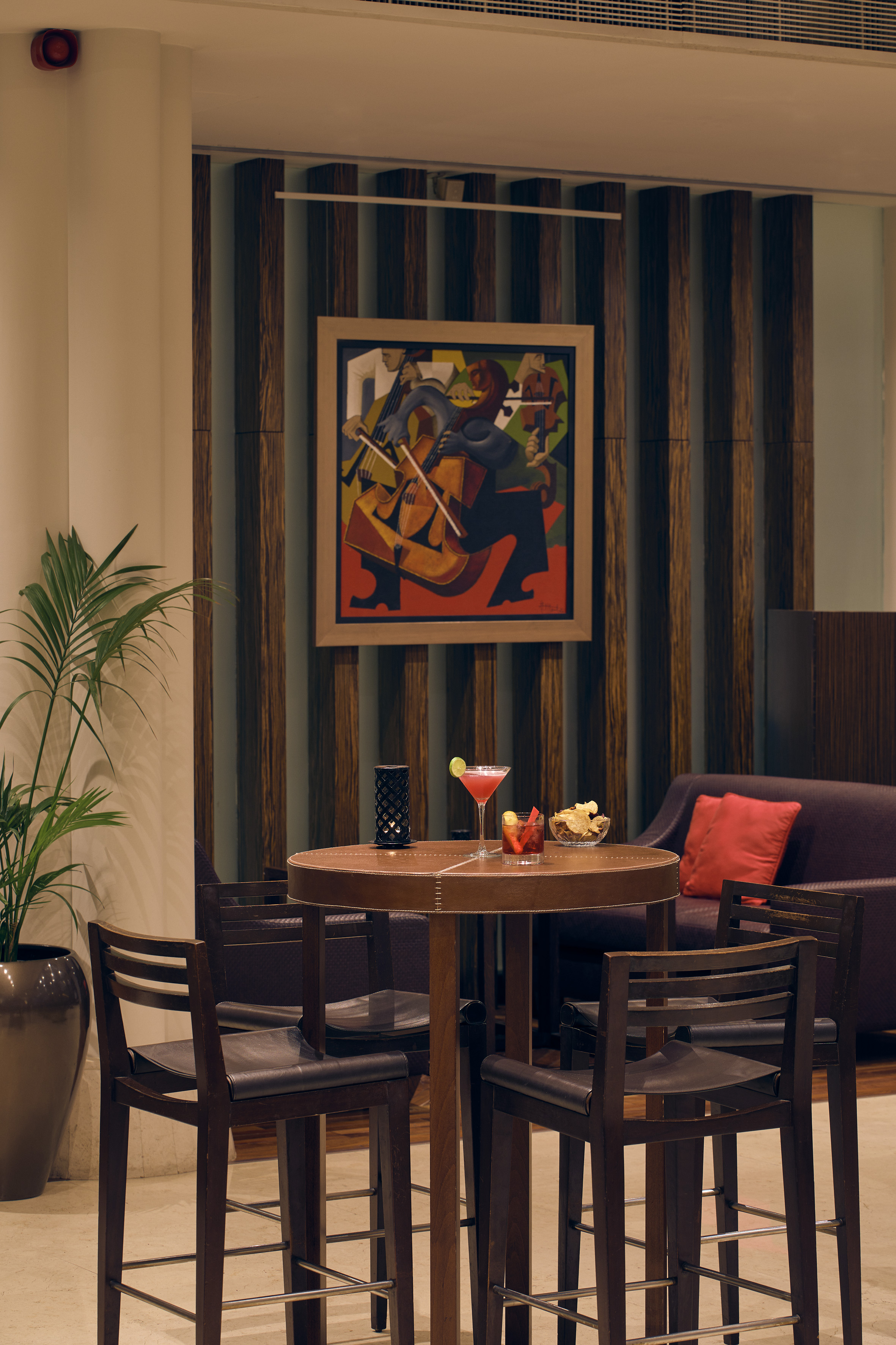 Stylish bar lounge with cocktails, abstract art, and wooden wall decor.