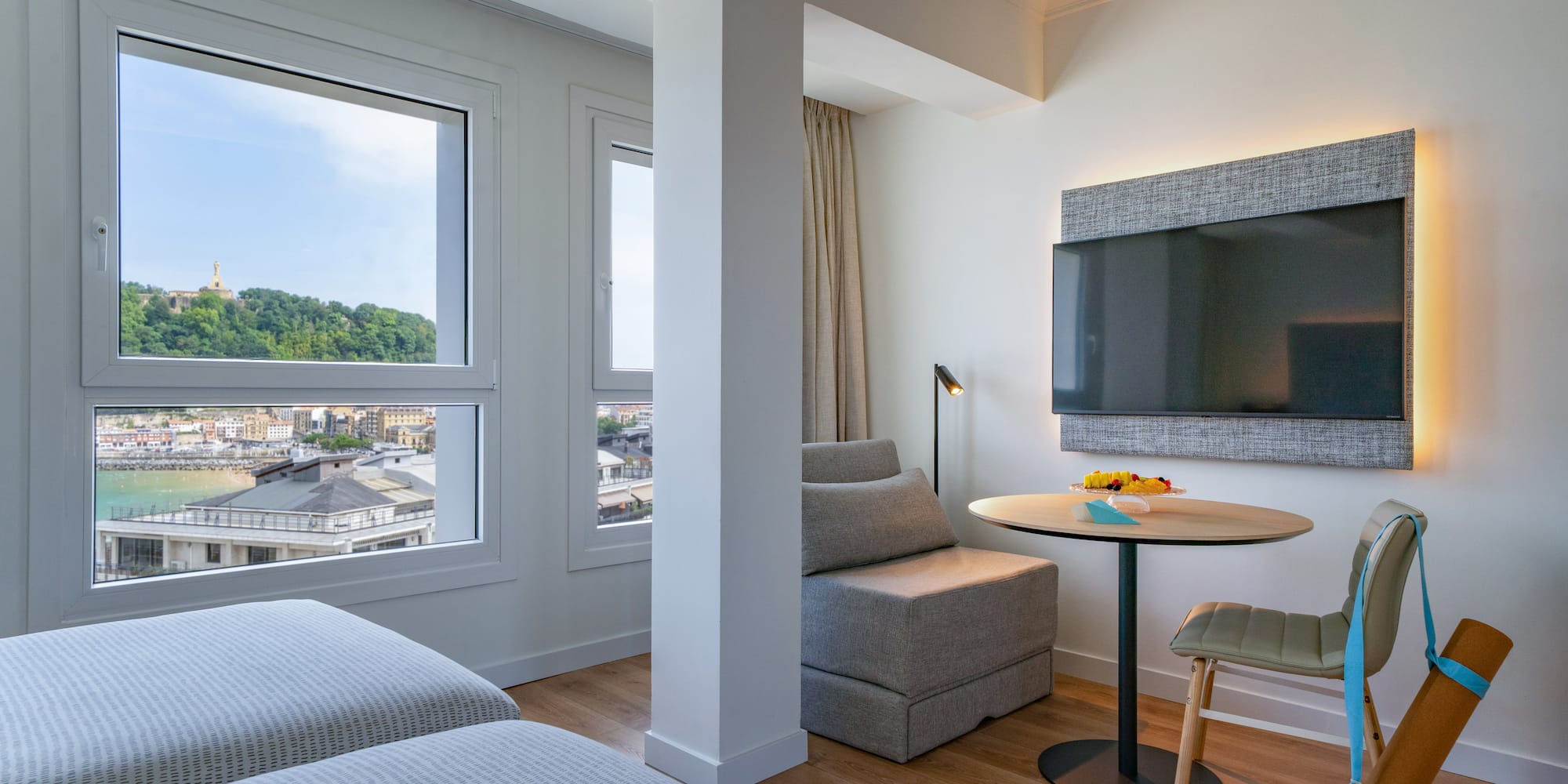 Suite moderna de hotel con vista a la bahía de San Sebastián, camas y TV.