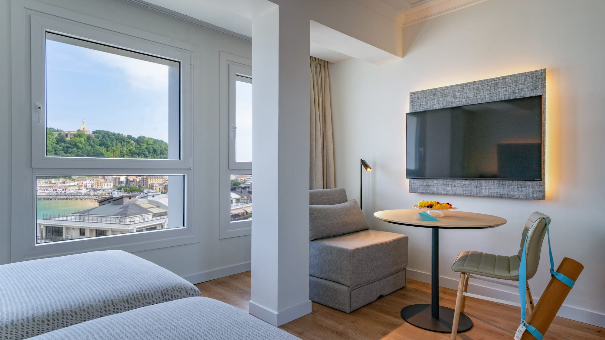 Suite moderna de hotel con vista a la bahía de San Sebastián, camas y TV.