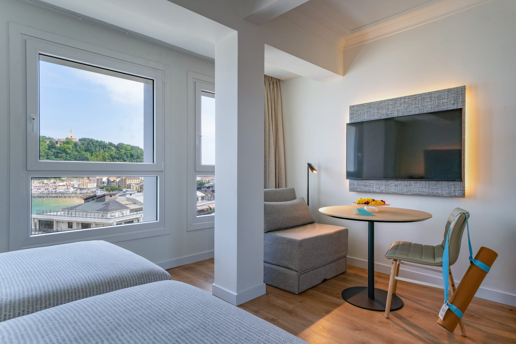 Suite moderna de hotel con vista a la bahía de San Sebastián, camas y TV.