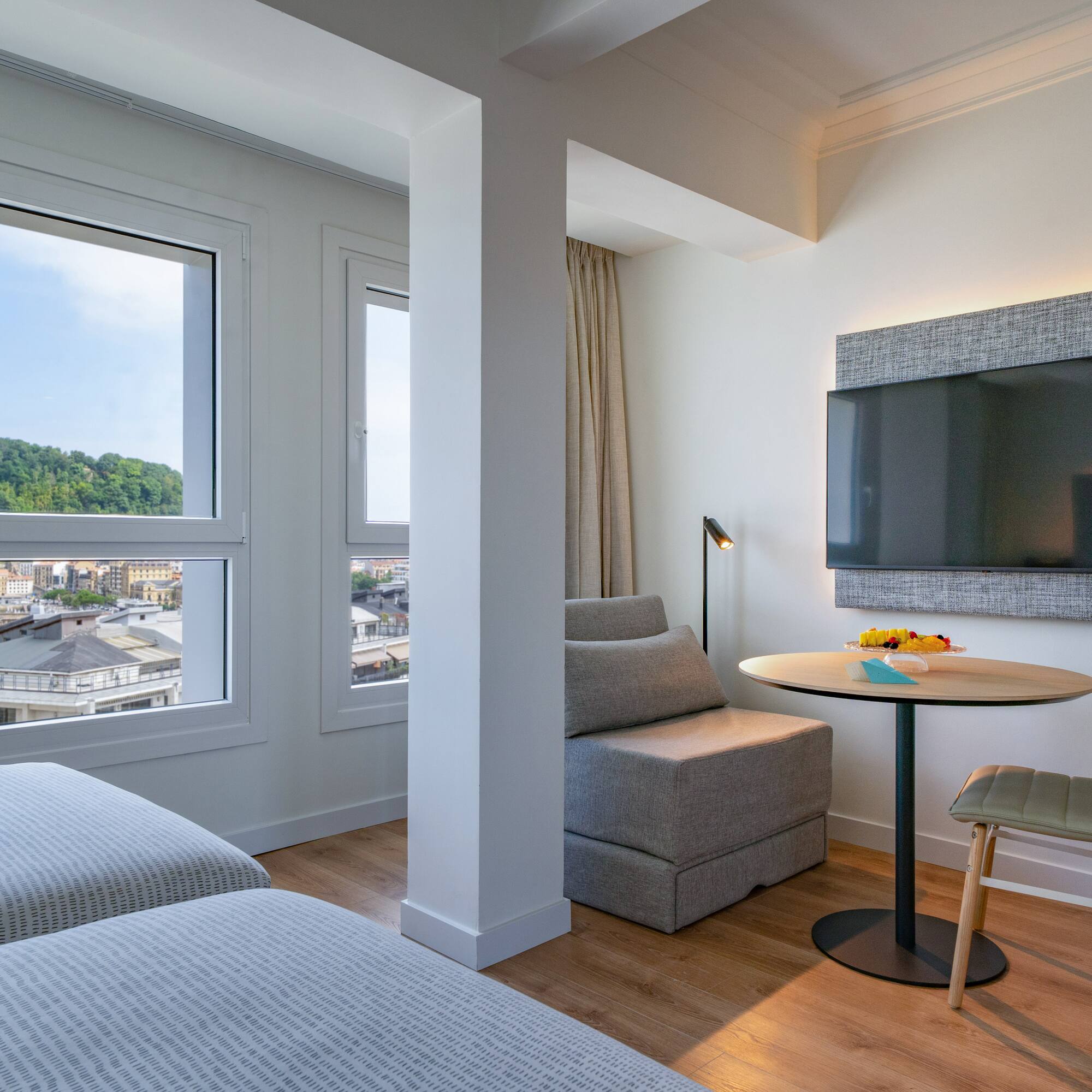 Suite moderna de hotel con vista a la bahía de San Sebastián, camas y TV.