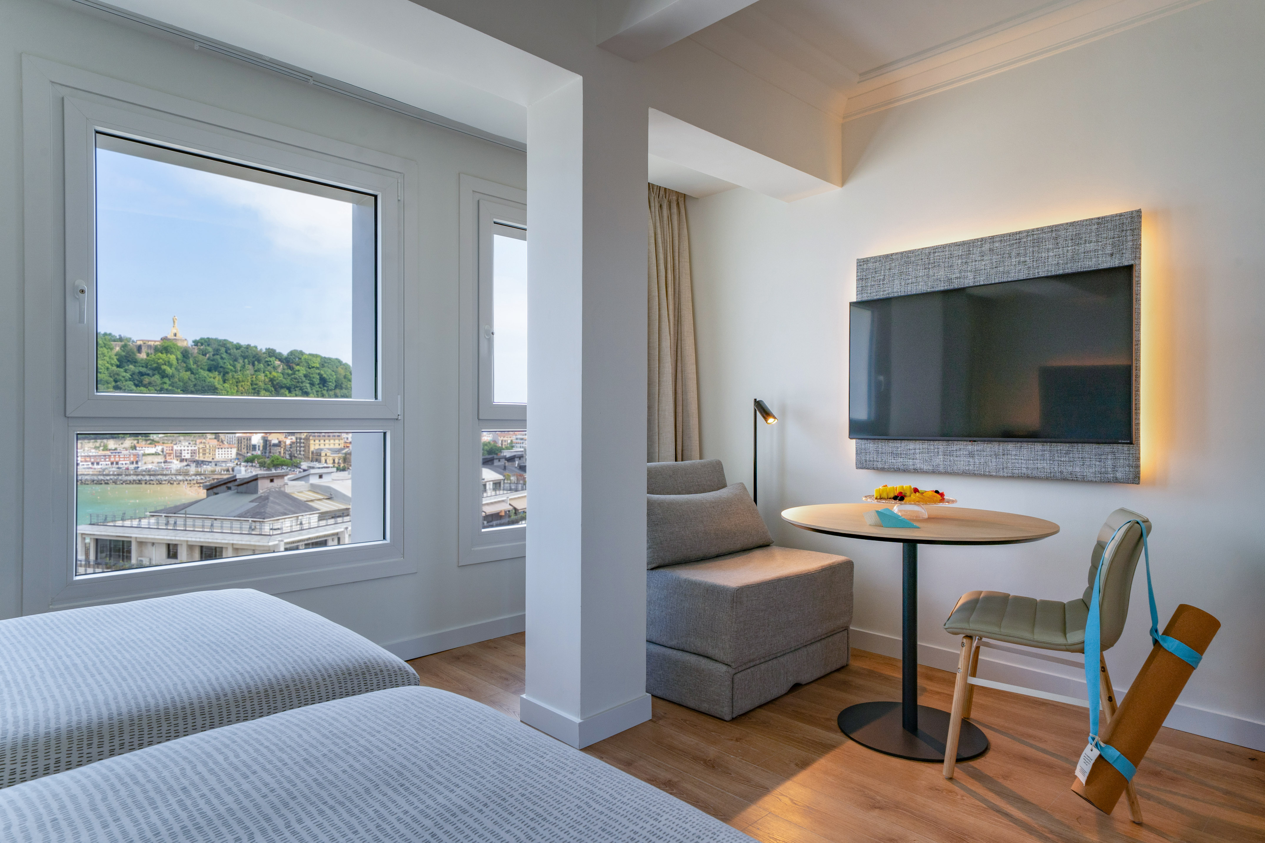 Suite moderna de hotel con vista a la bahía de San Sebastián, camas y TV.