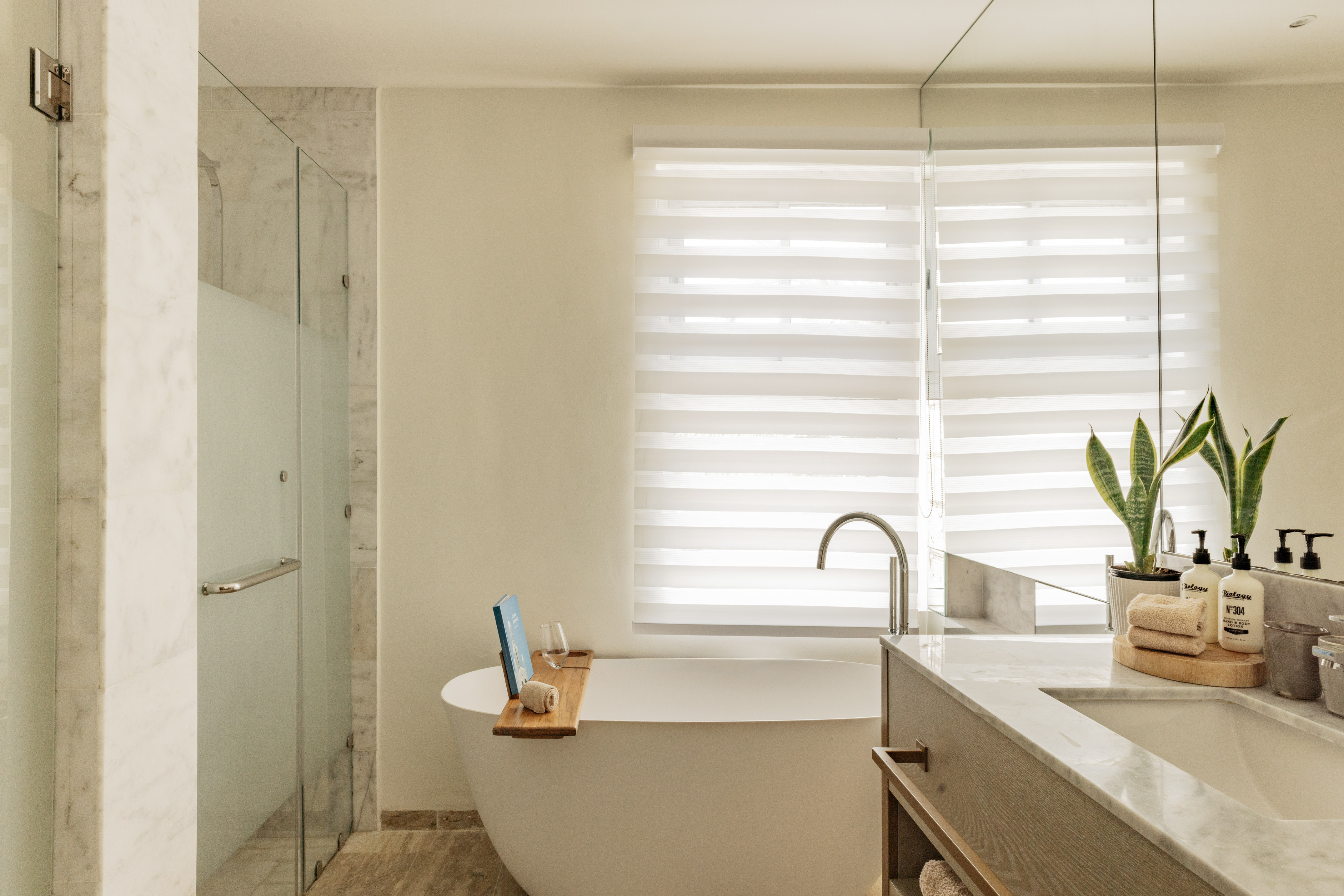Modern luxury bathroom with freestanding tub, glass shower, and marble vanity.