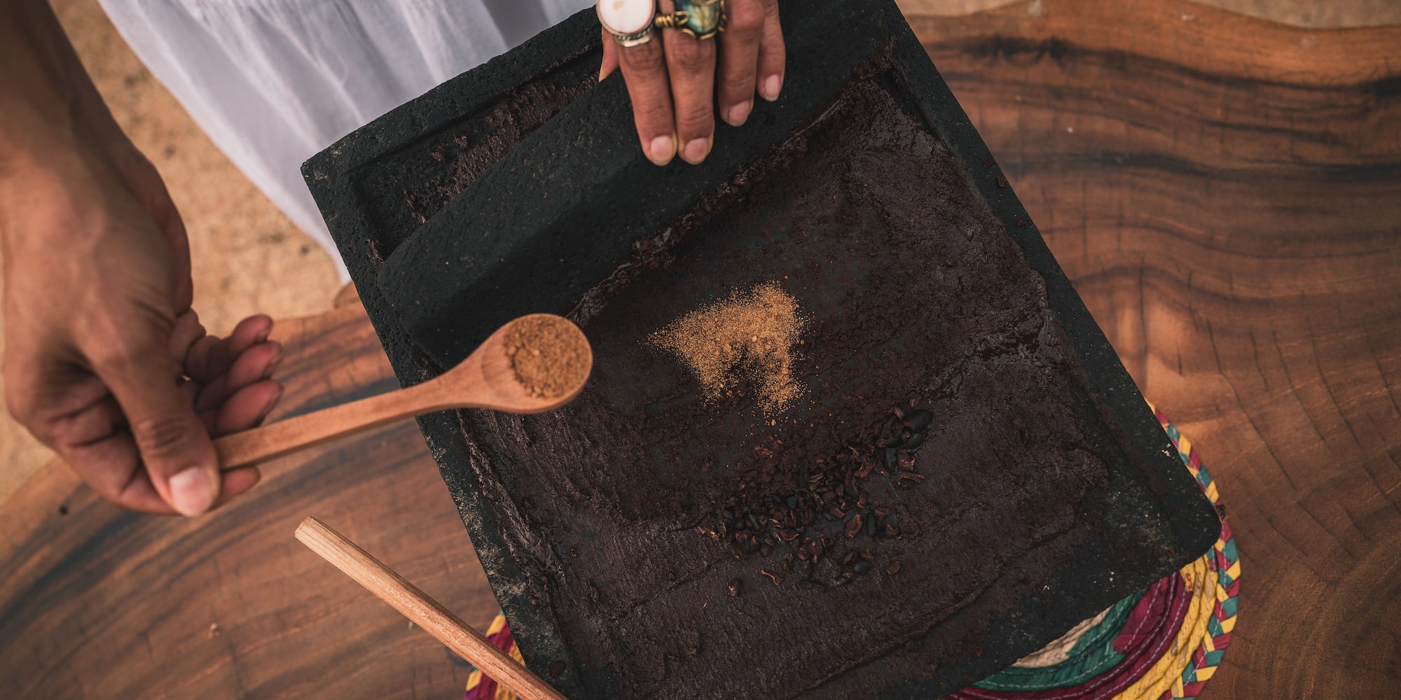 a person holding a spoon over a black square with brown powder