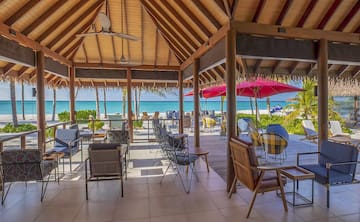 a beach covered patio with chairs and umbrellas