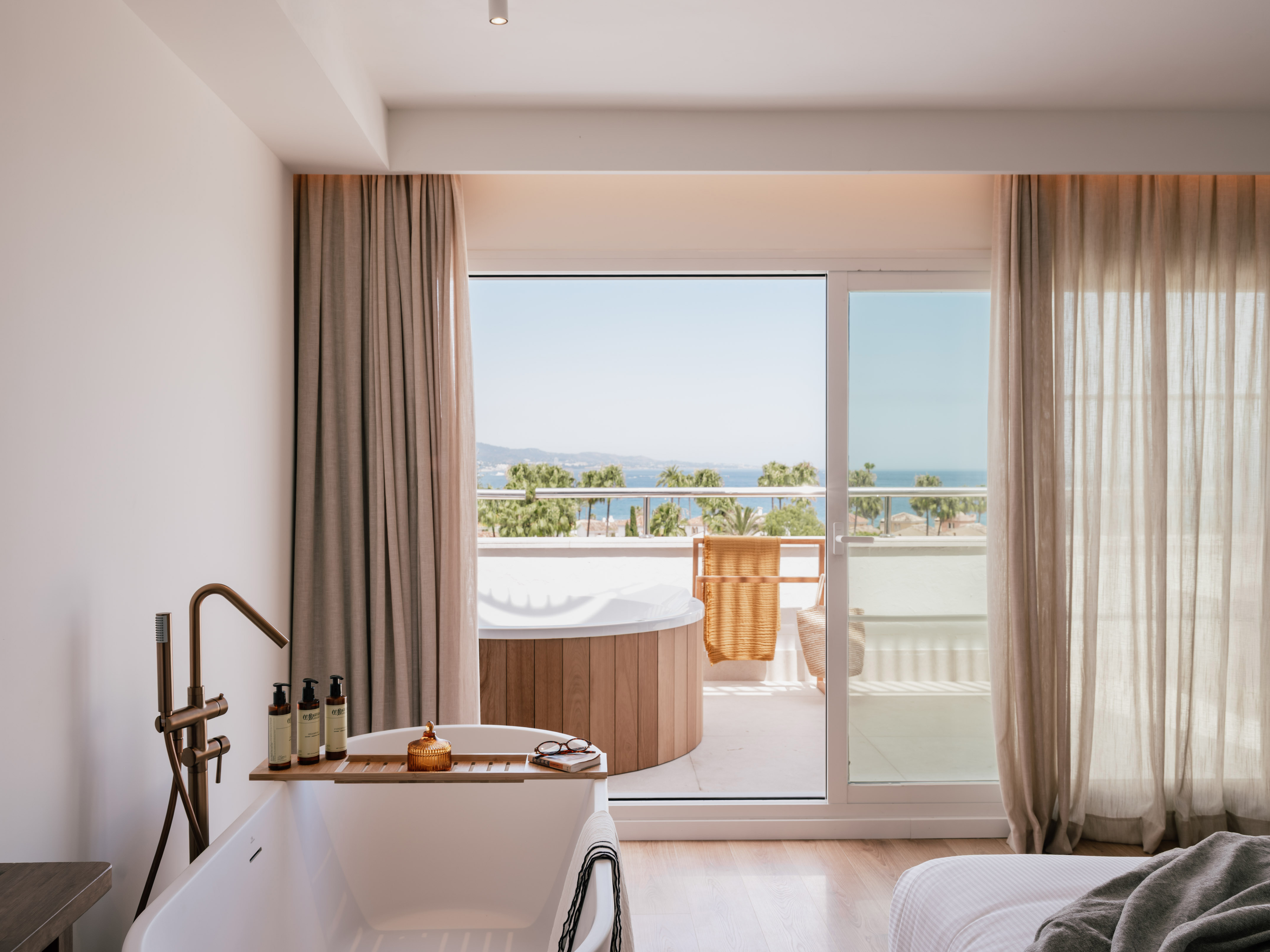 Luxury hotel room with bathtub, balcony hot tub, and stunning sea view.
