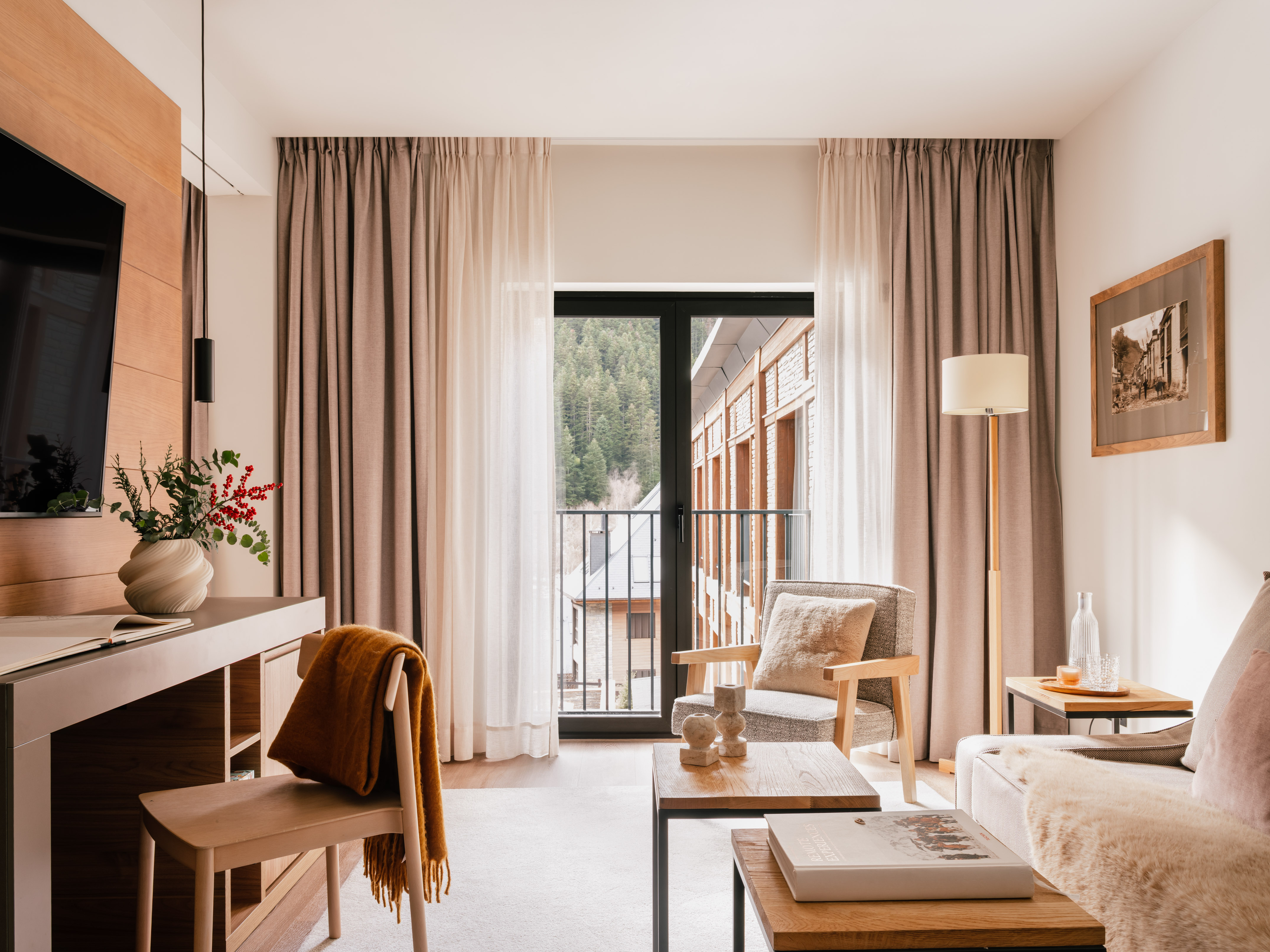 Cozy hotel suite living area with mountain view balcony, modern decor.