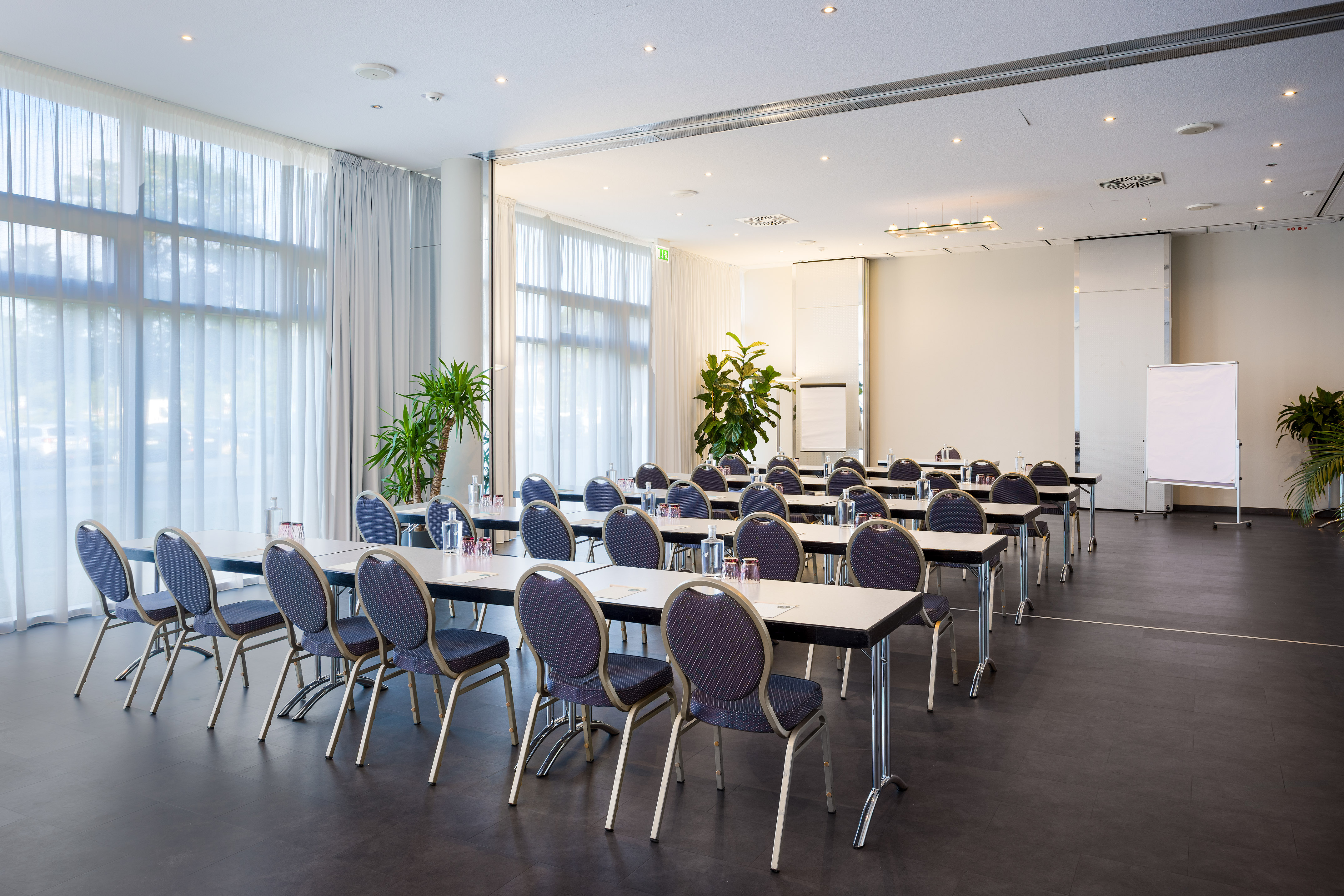 Conference room with classroom seating, tables, chairs, large windows, and whiteboard.