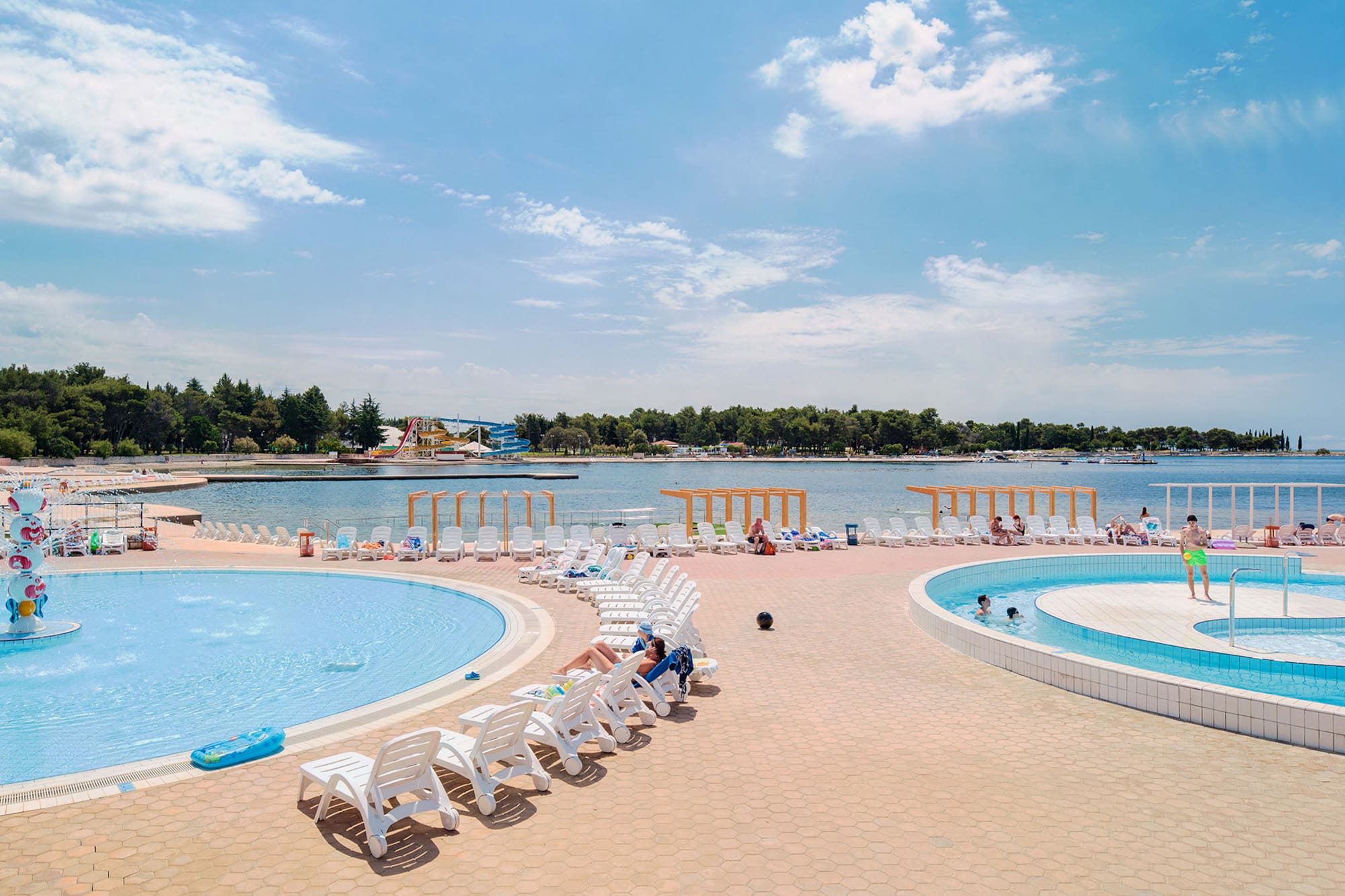 a pool with chairs and a body of water