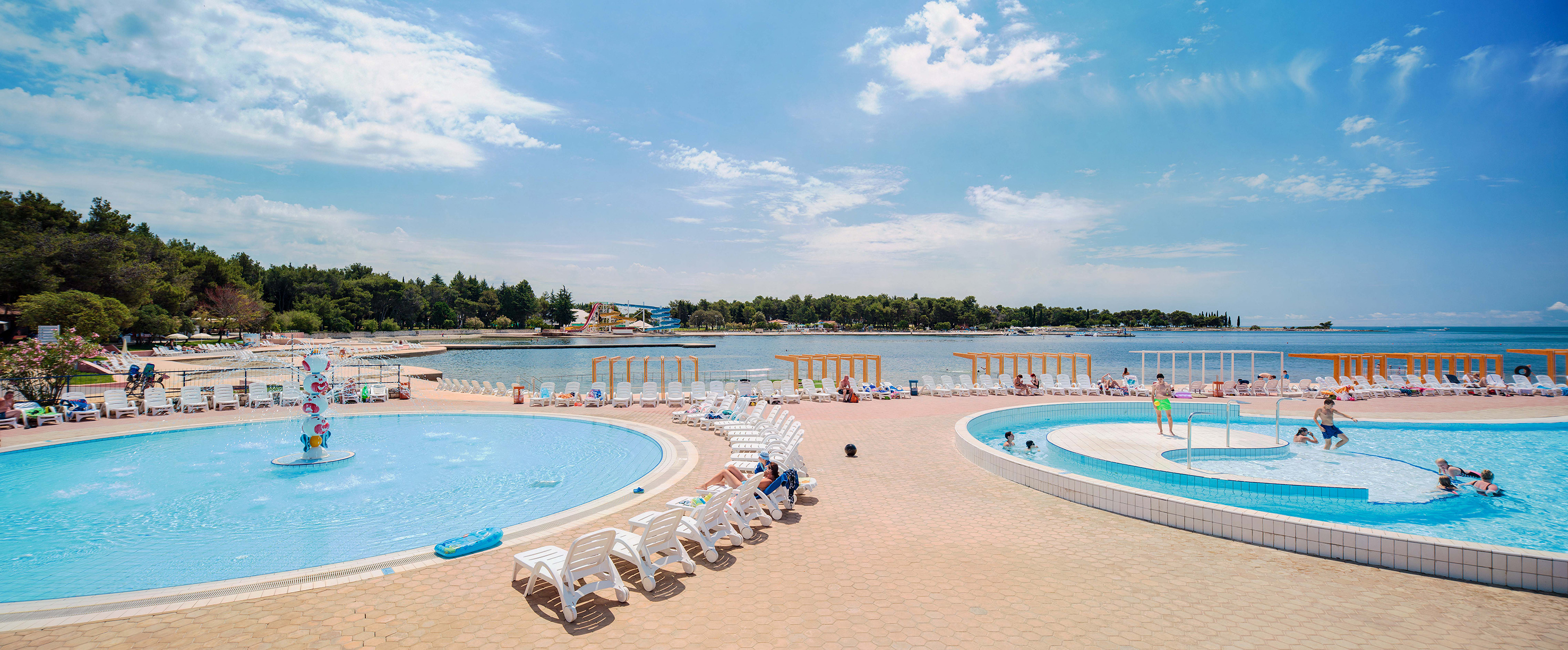 a pool with chairs and a body of water