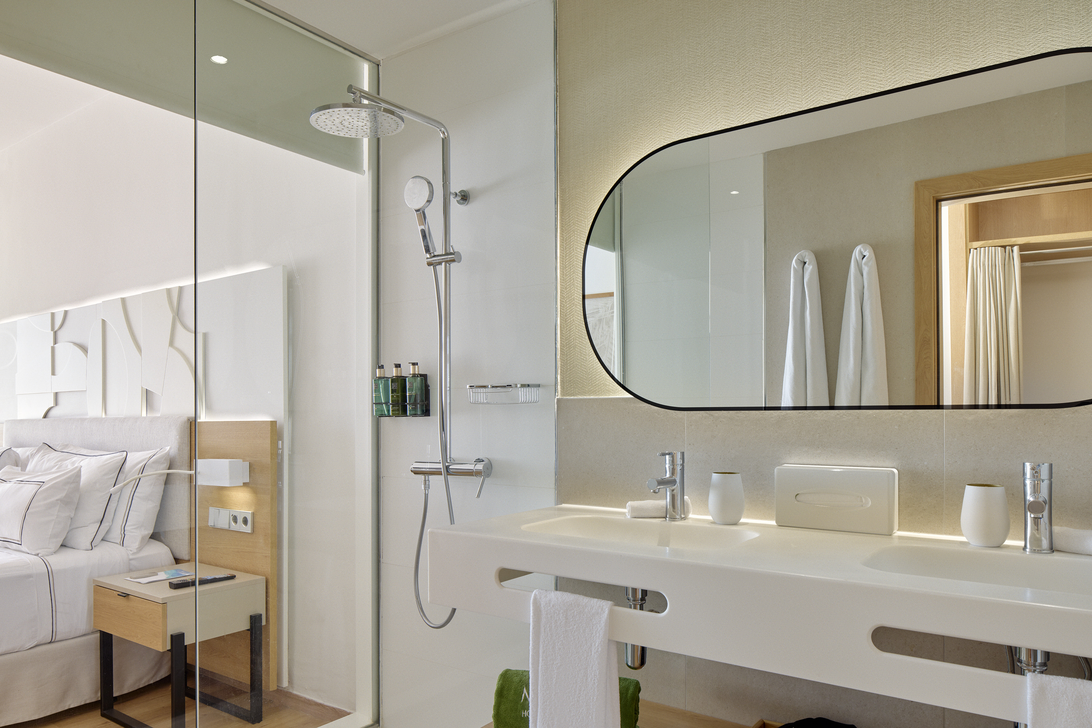 Luxury hotel bathroom: glass shower, double vanity, illuminated mirror.