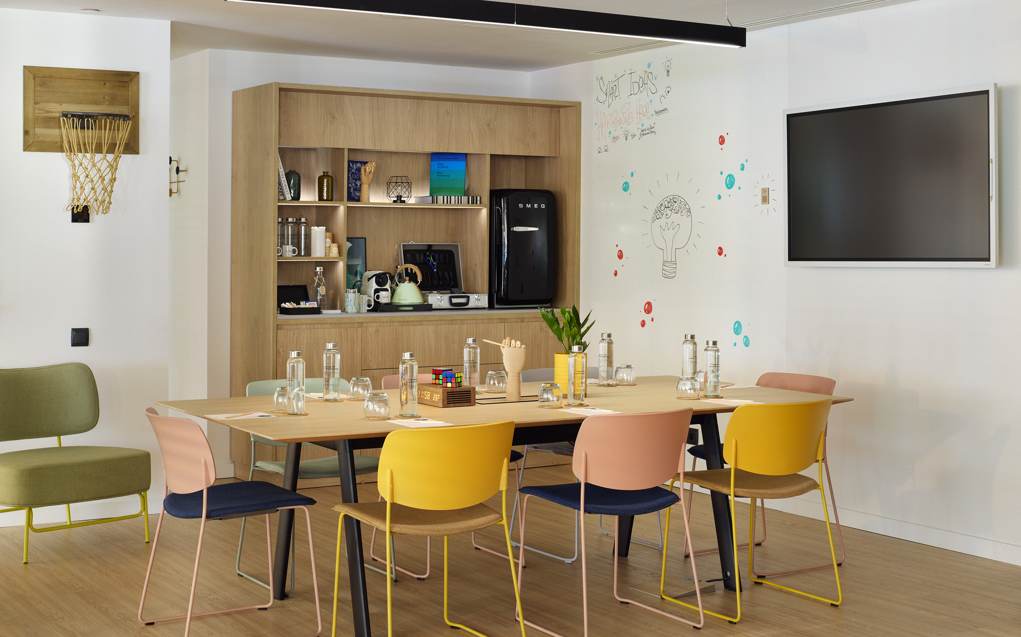 Creative meeting room with colorful chairs, whiteboard, TV, and kitchenette.